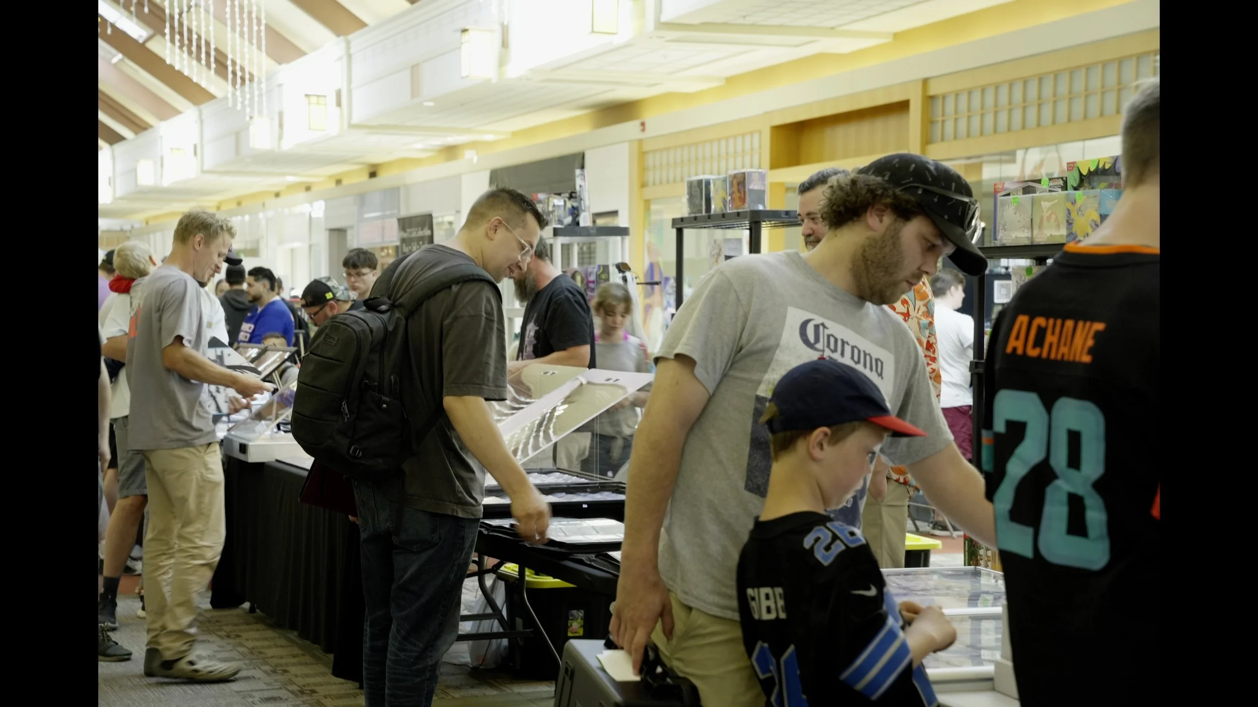 Crowded convention hall with people browsing collectible merchandise at vendor tables