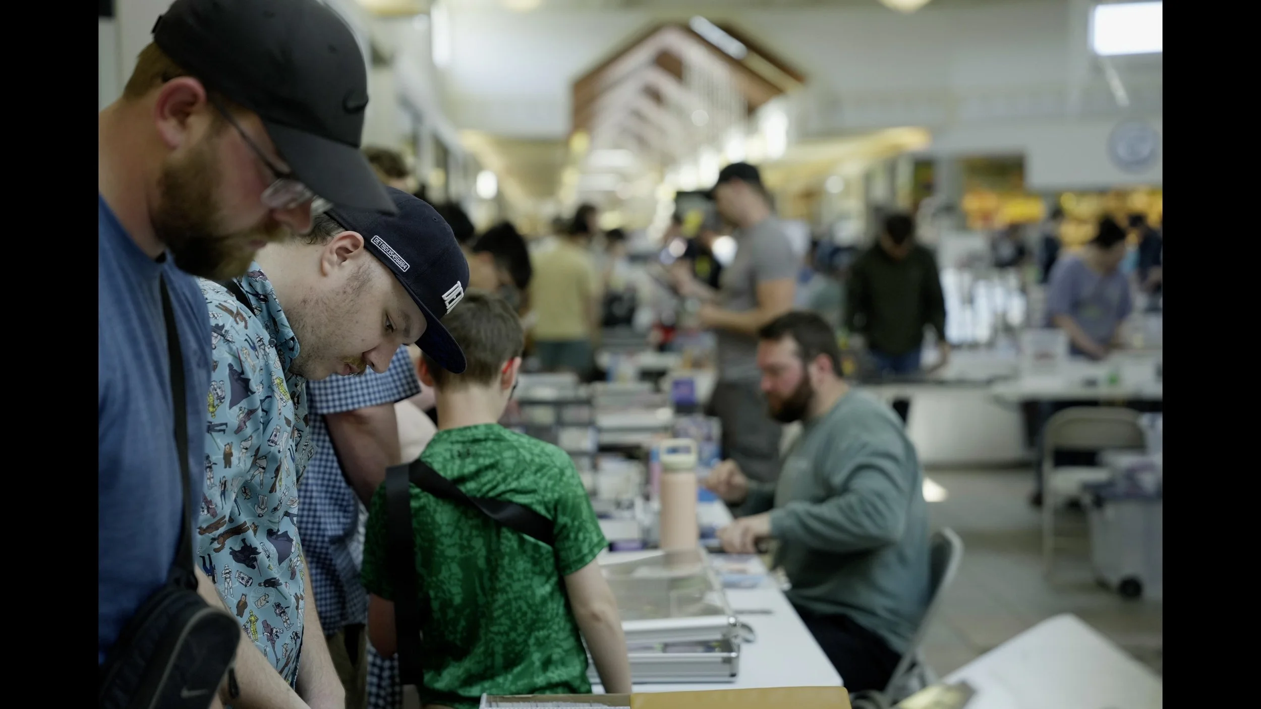 Busy indoor comic convention with attendees browsing merchandise at vendor tables