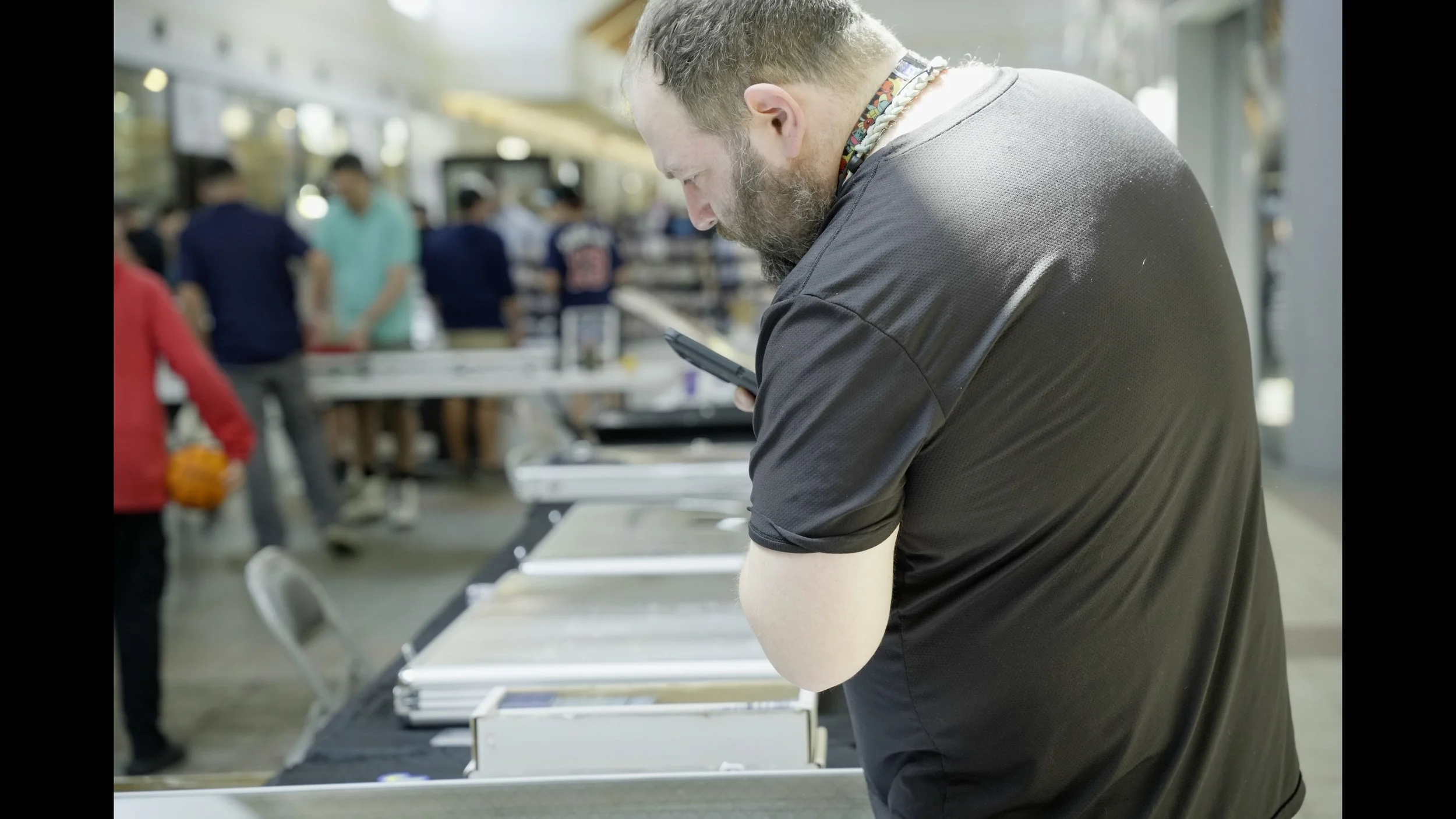 Man looking at a smartphone beside airport security screening trays