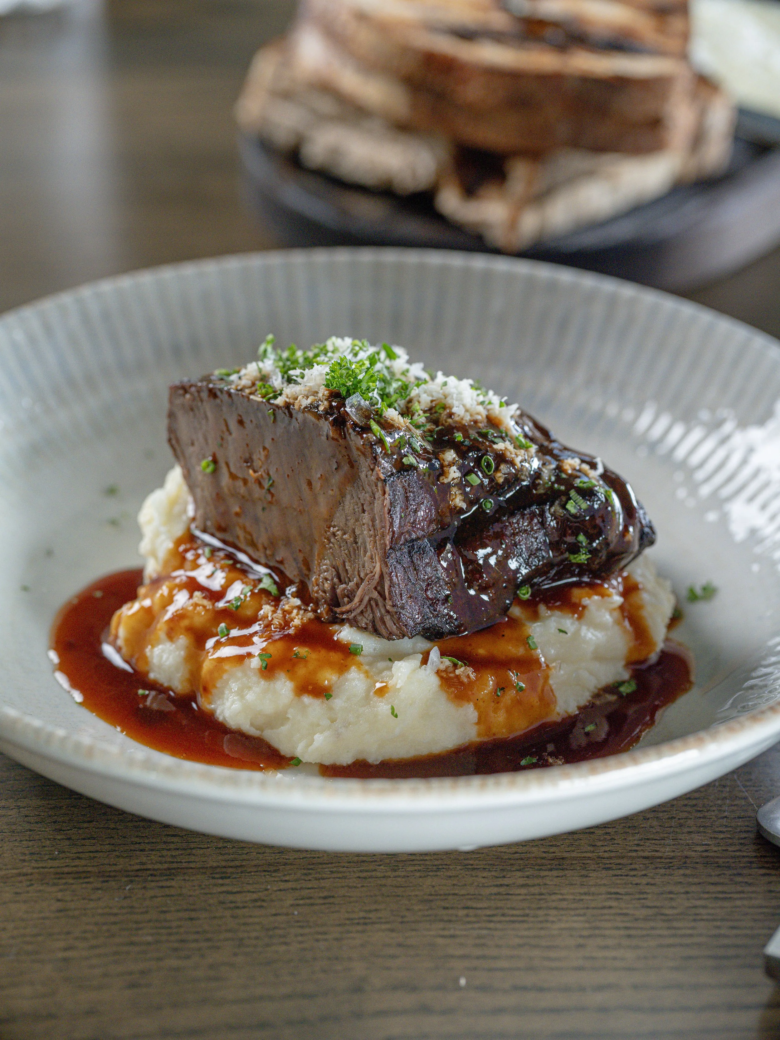 Glazed braised beef short rib topped with herbs and breadcrumbs, served over mashed potatoes with brown gravy