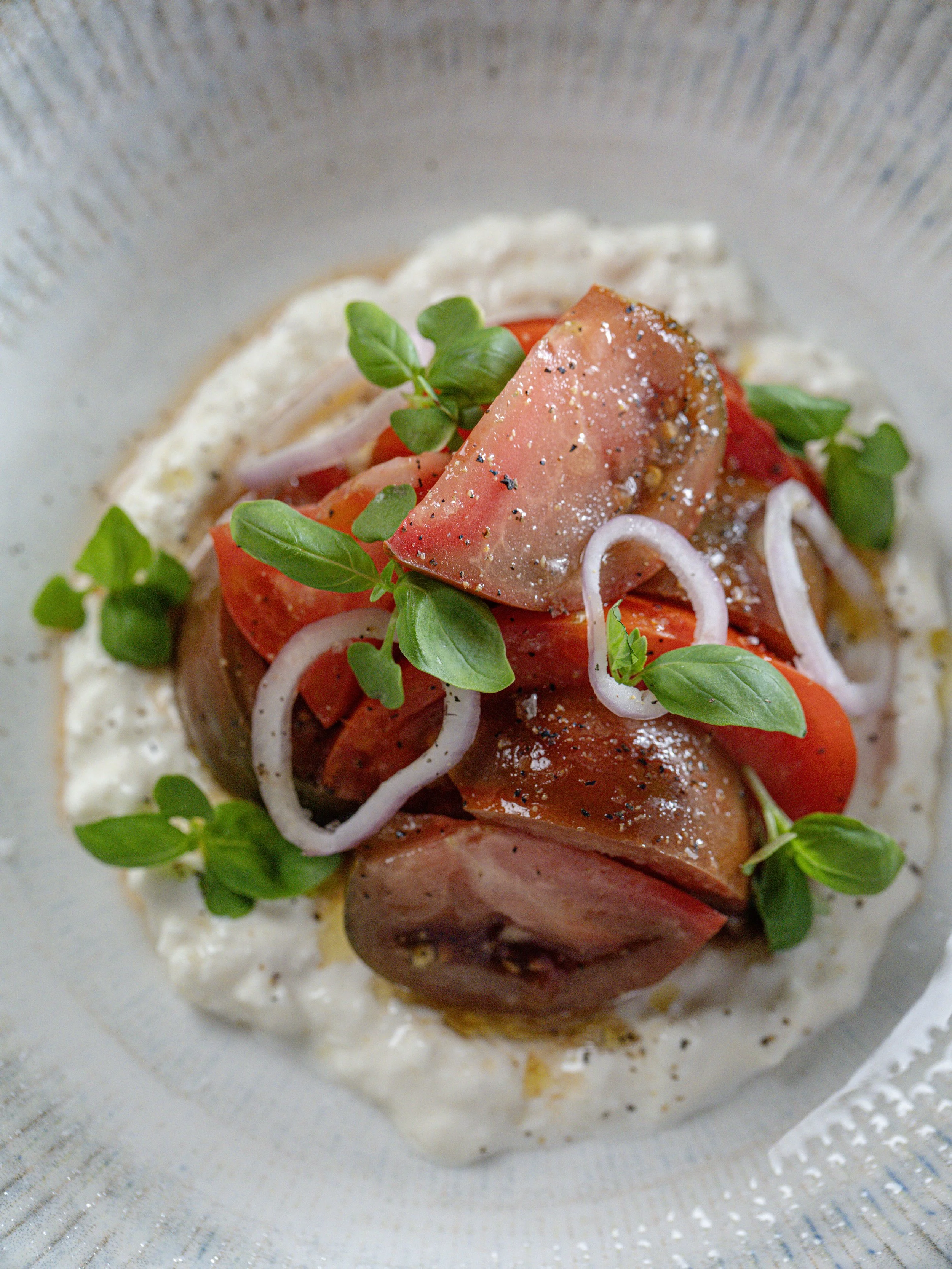 Close-up of seared tuna steak over rice with tomatoes, red onion, and fresh greens
