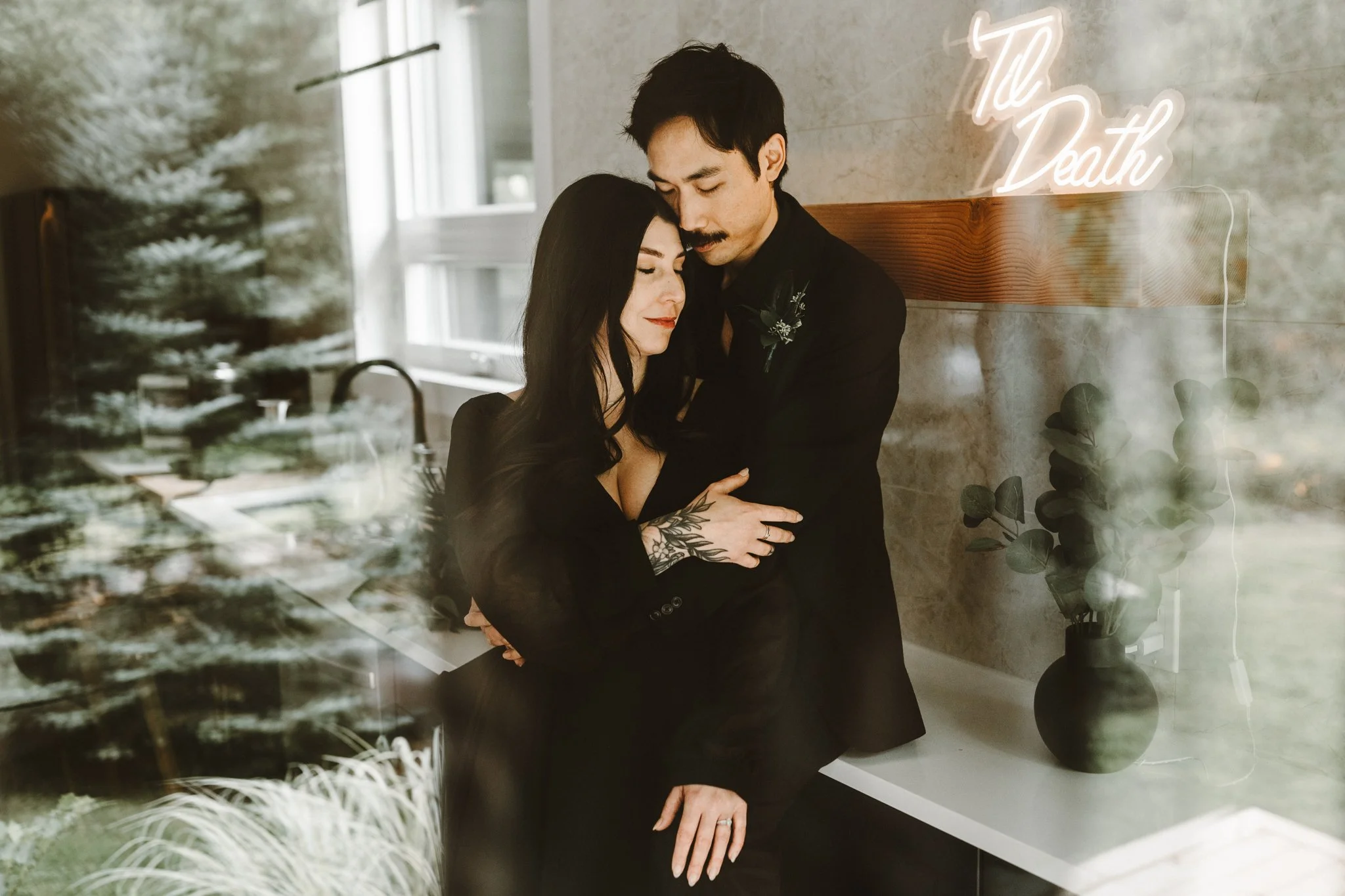 goth couple shot through window as they embrace
