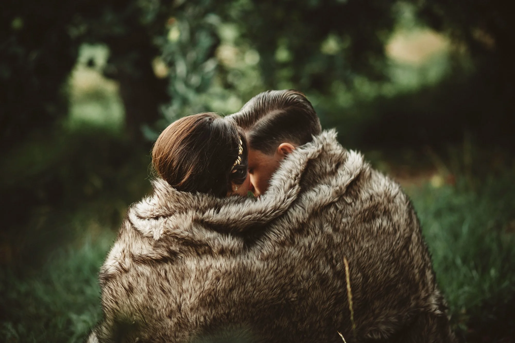 couple in apple orchard cuddling in fur blanket