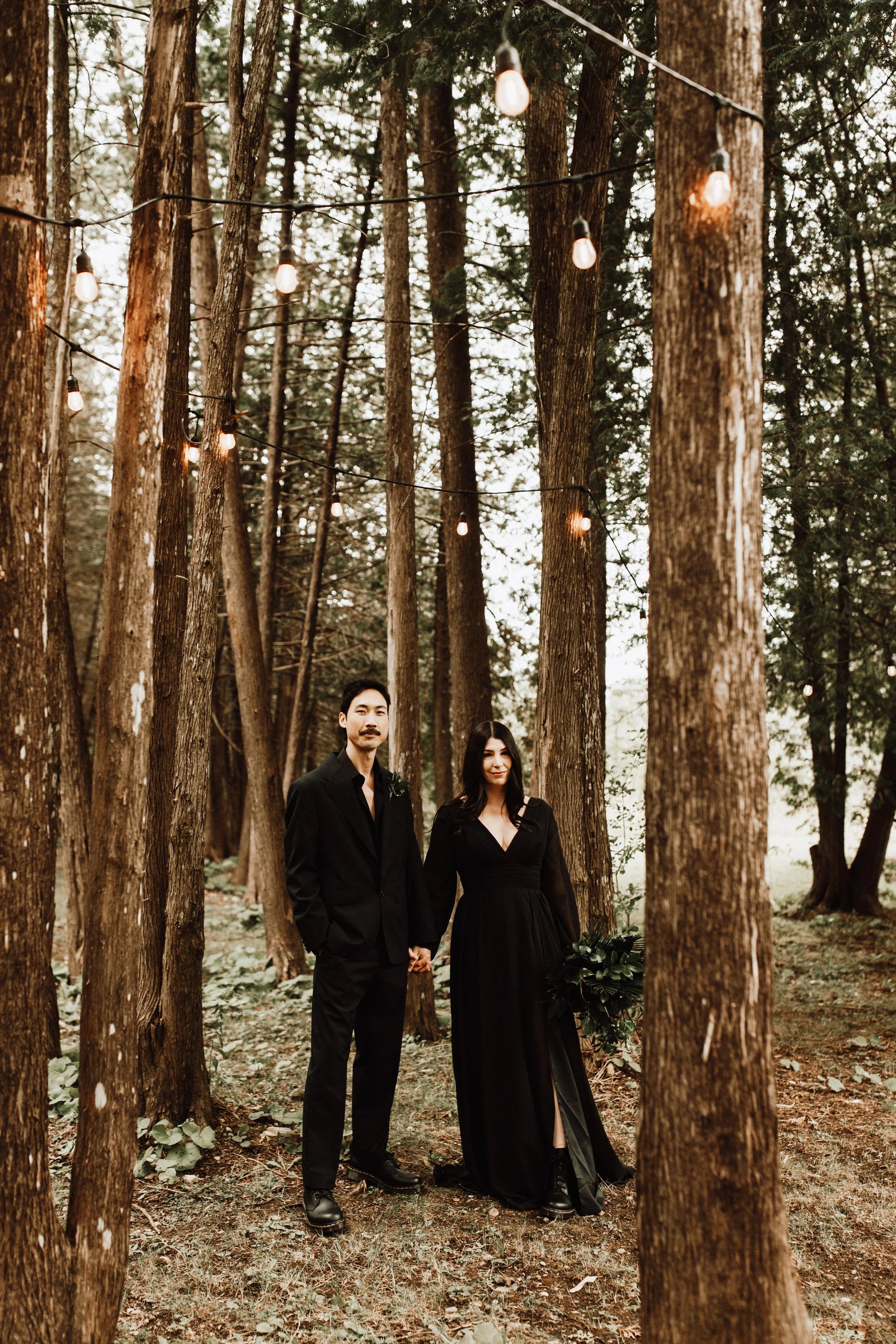 gothic couple standing in the forest holding hands 