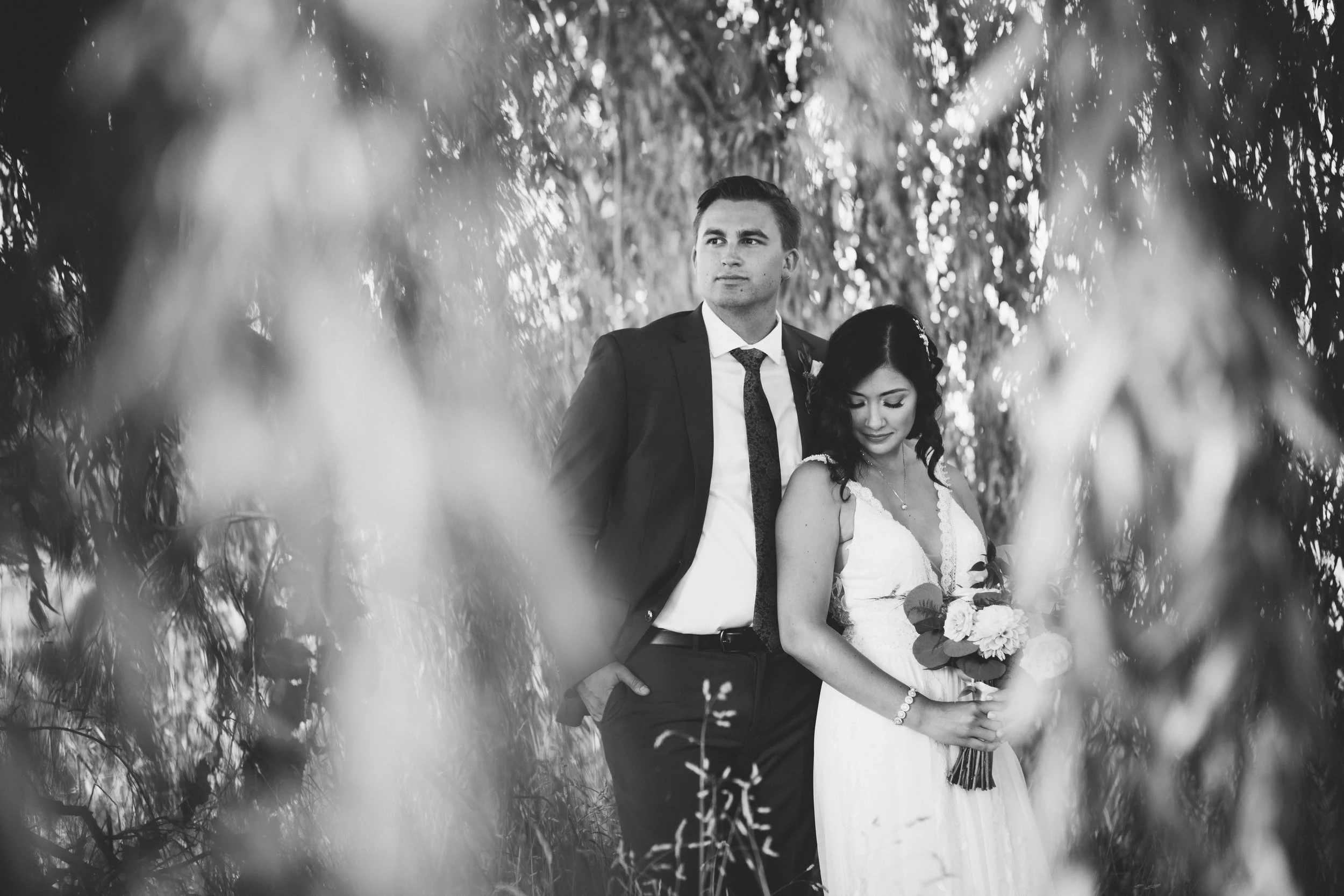 bride and groom posing in a willow tree