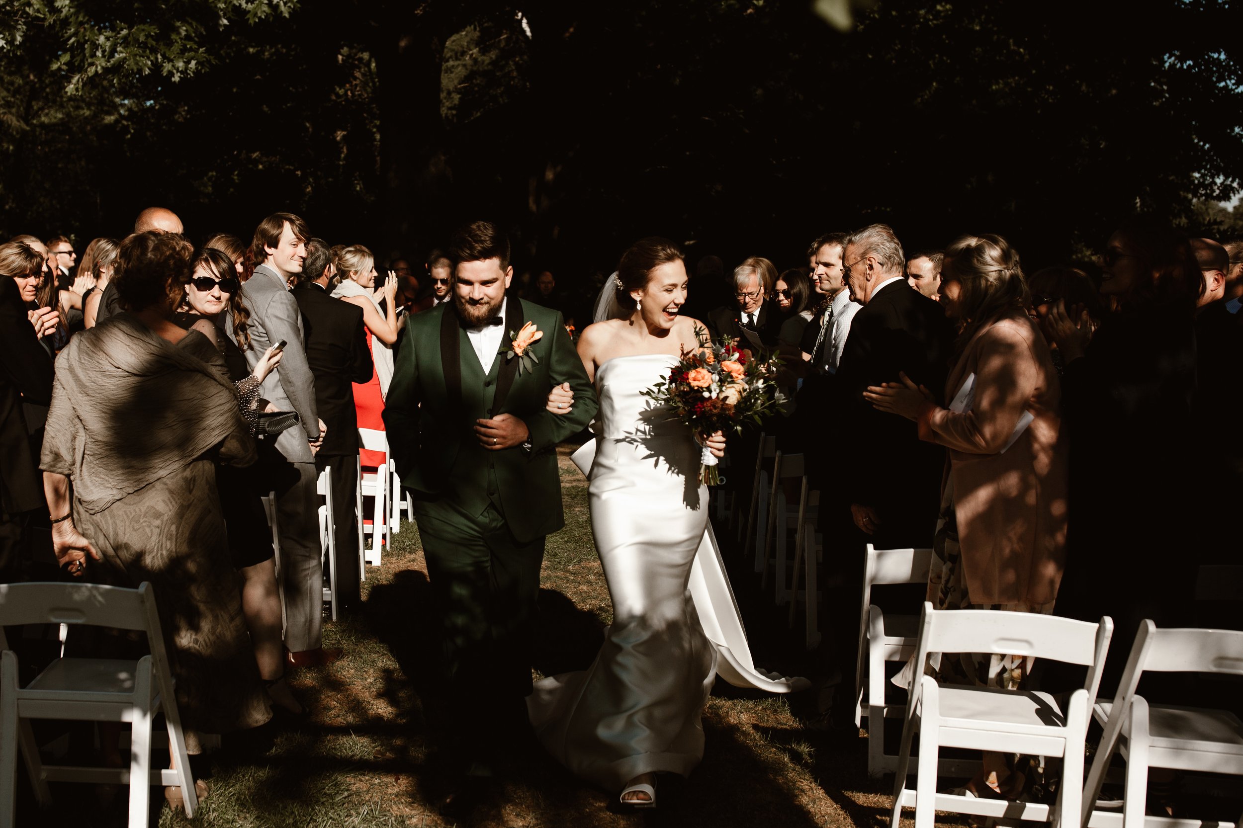 Happy newlyweds, all smiles as they return down the aisle in hard light