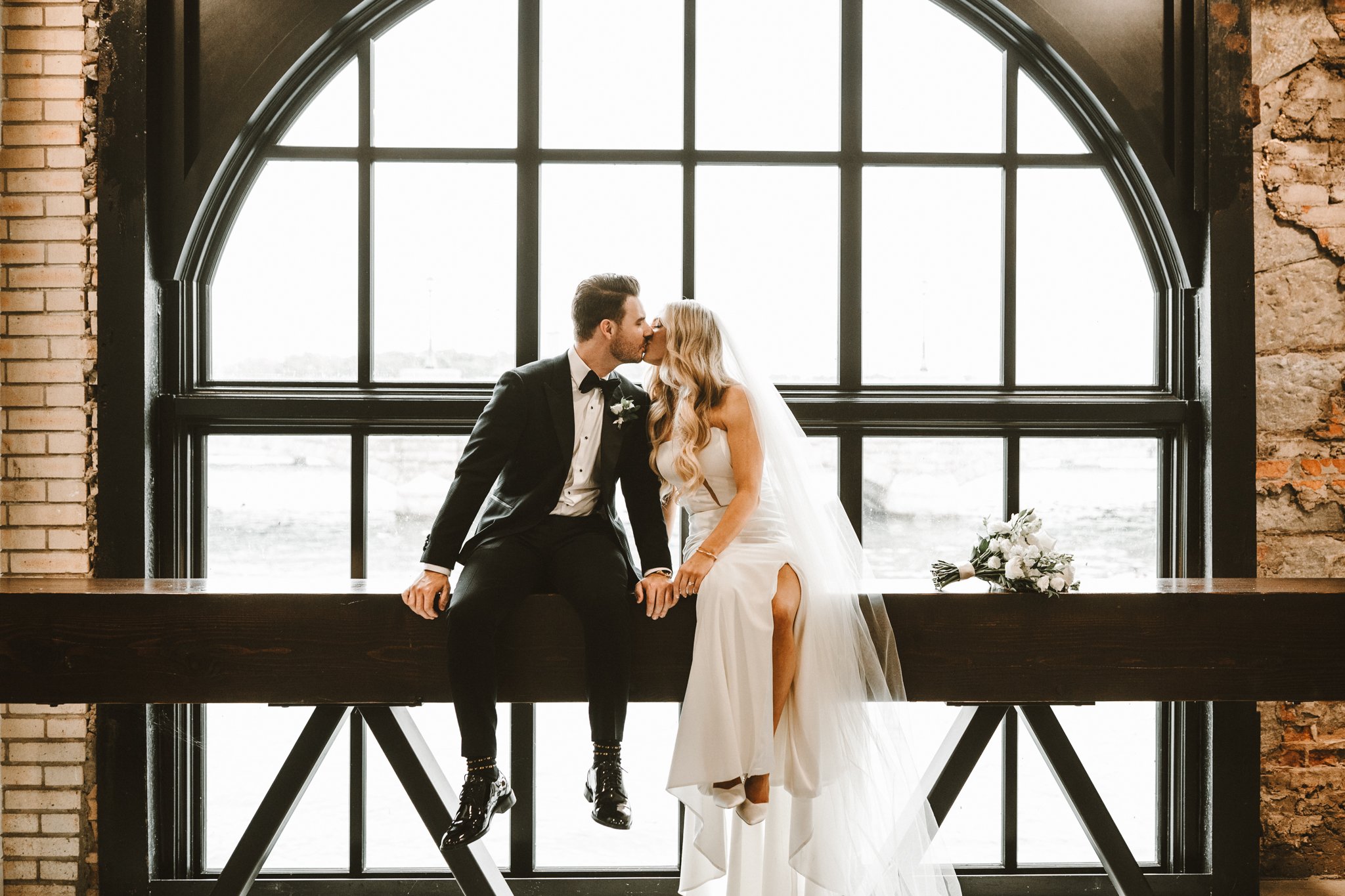 bride and groom kissing in front of bay window at niagara falls power plant