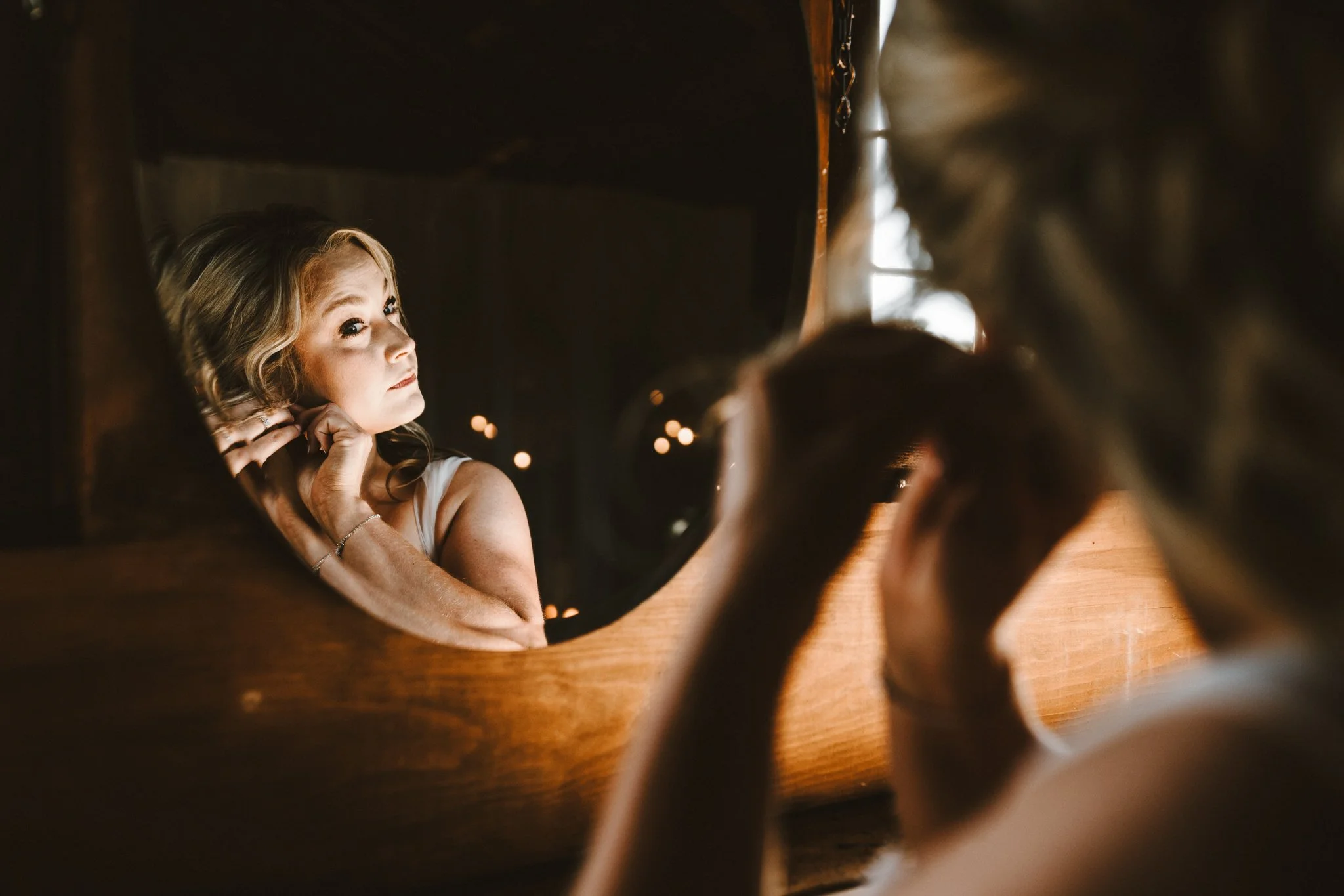 bride in mirror putting her earing in 