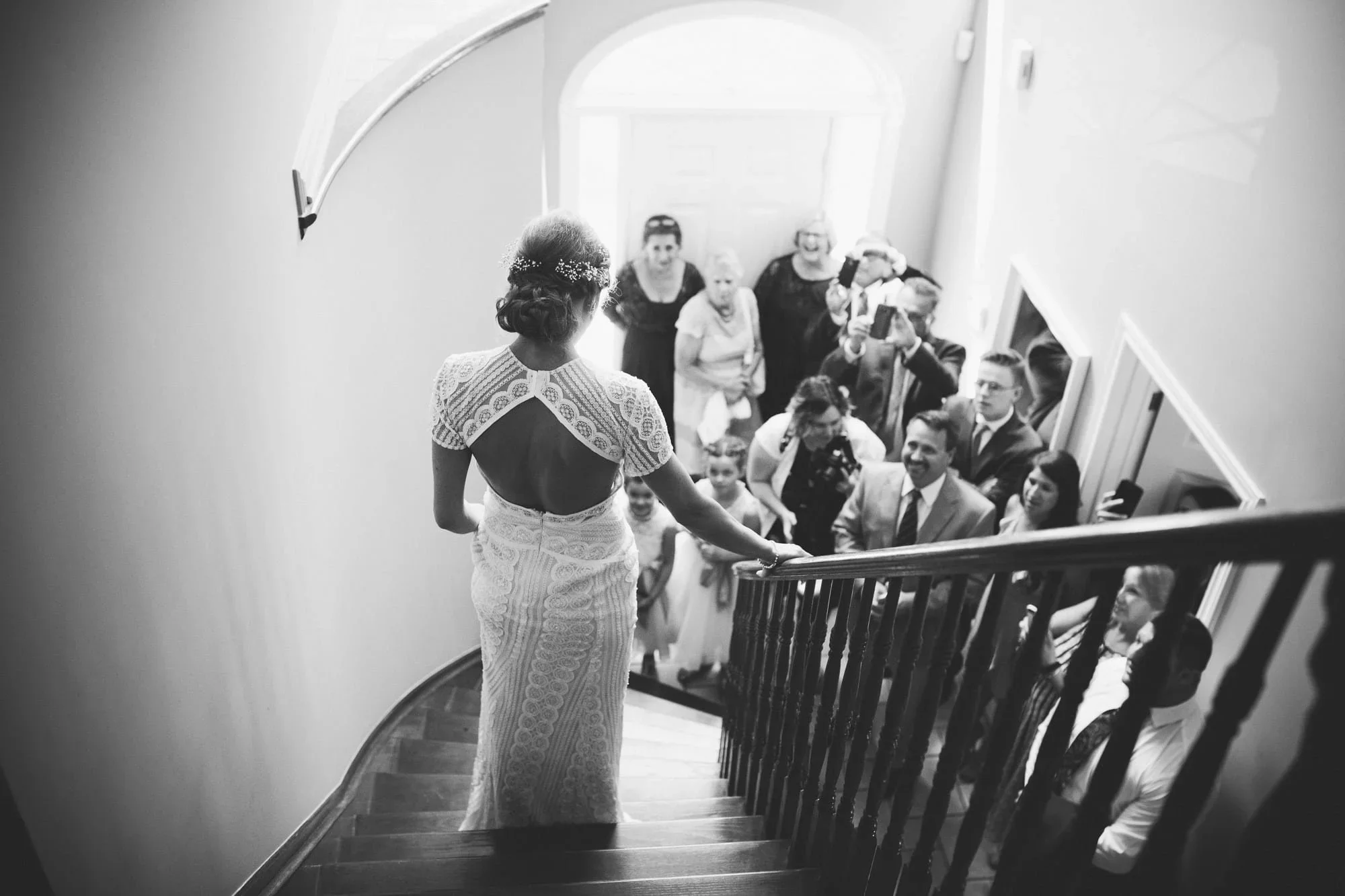 bride on staircase while bridal party looks on
