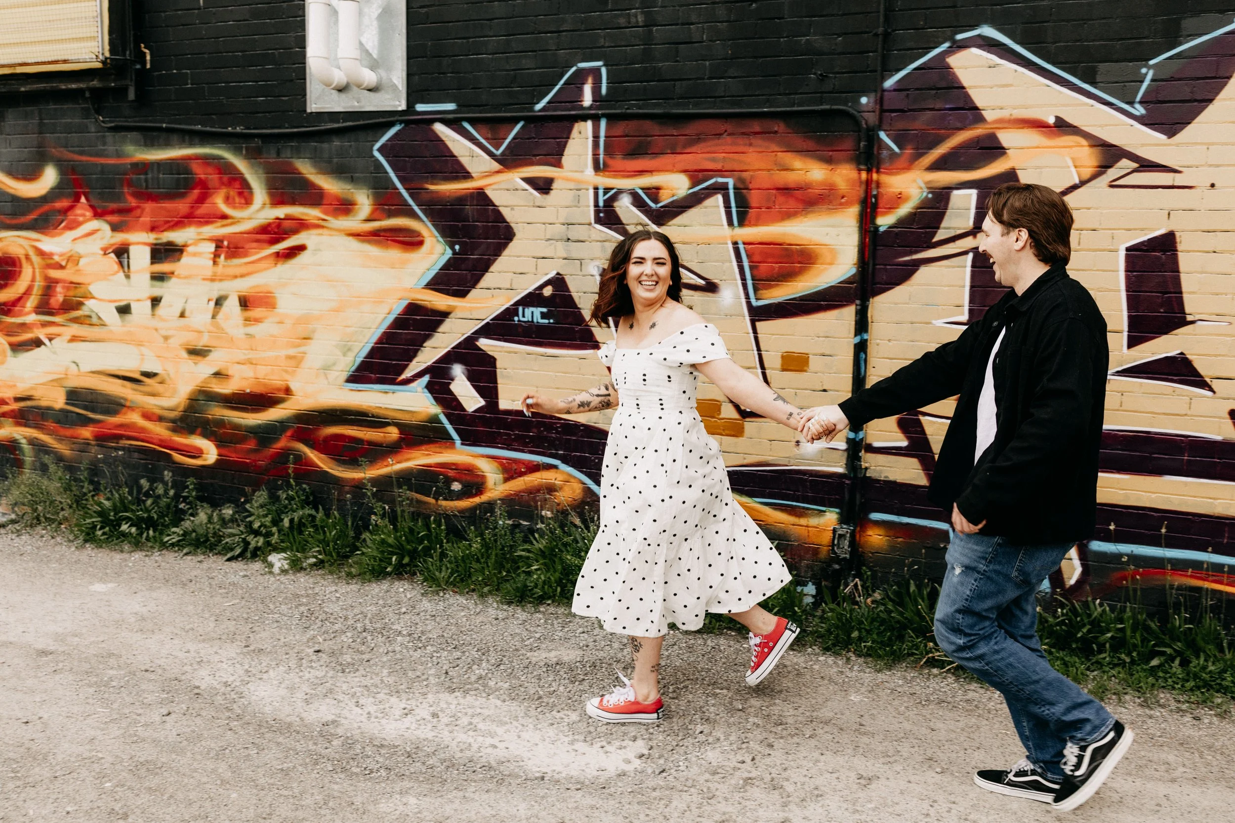 beautiful couple running and laughing in front of a graffiti wall