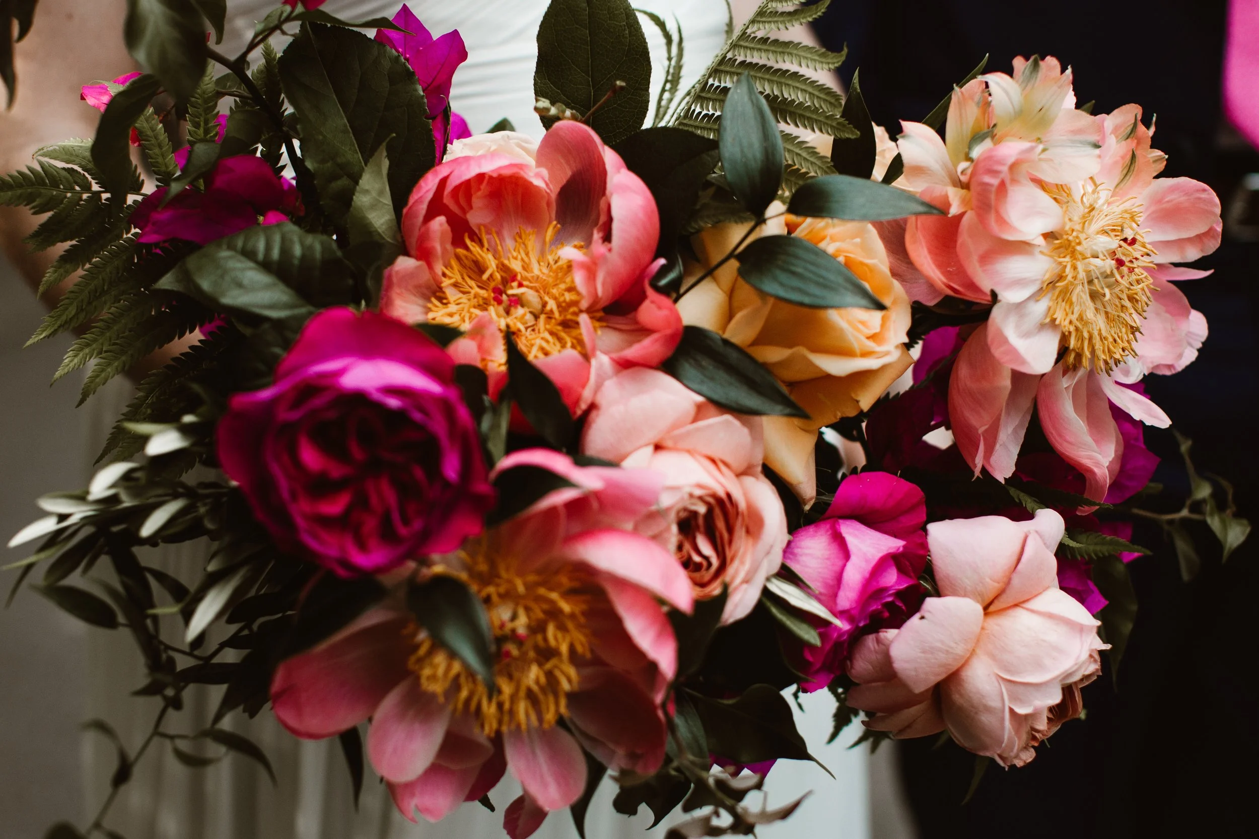 Close-up bouquet of pink, coral, peach, and magenta flowers with green foliage