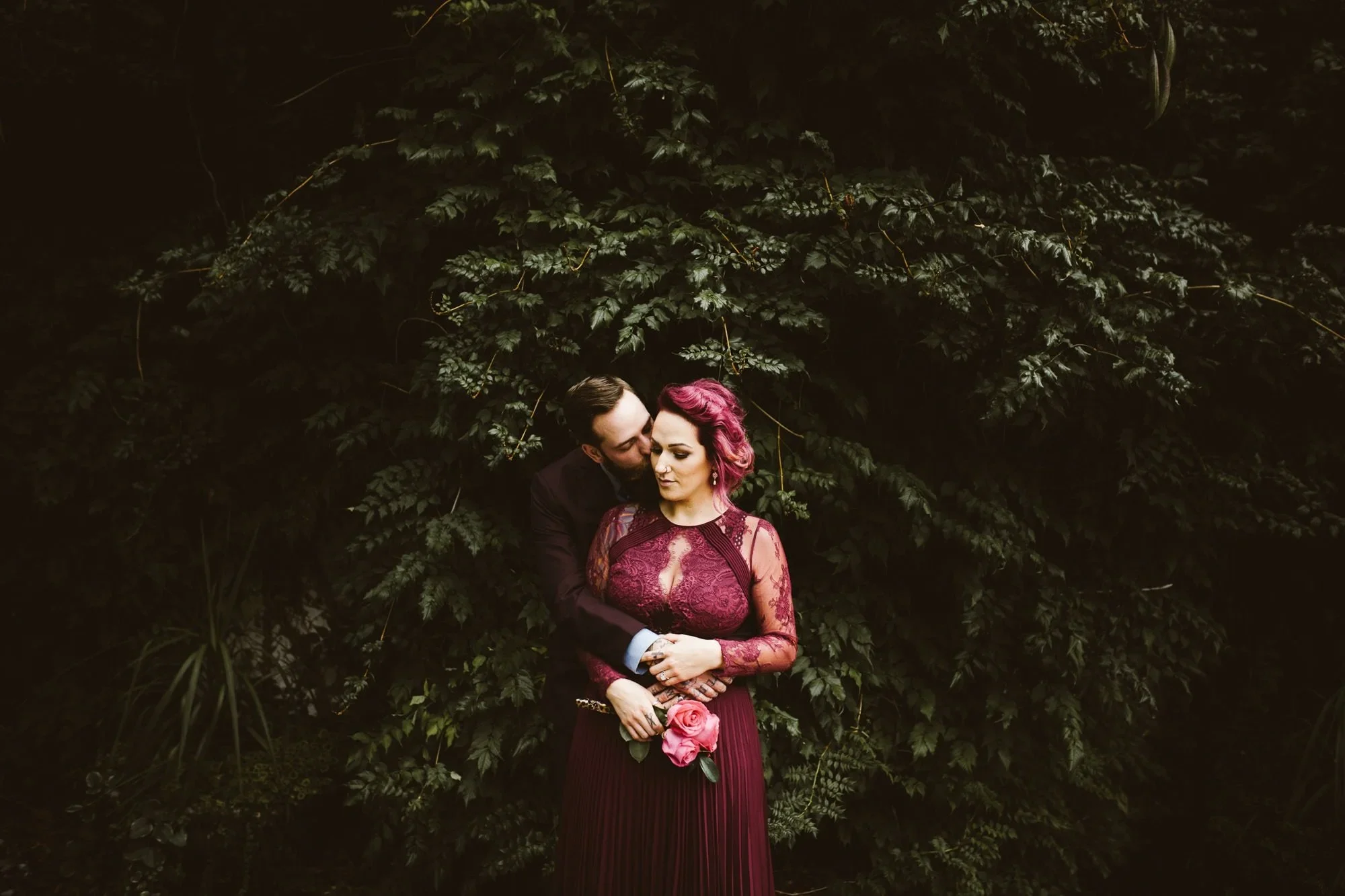 bride and groom embracing in front of ivy wall