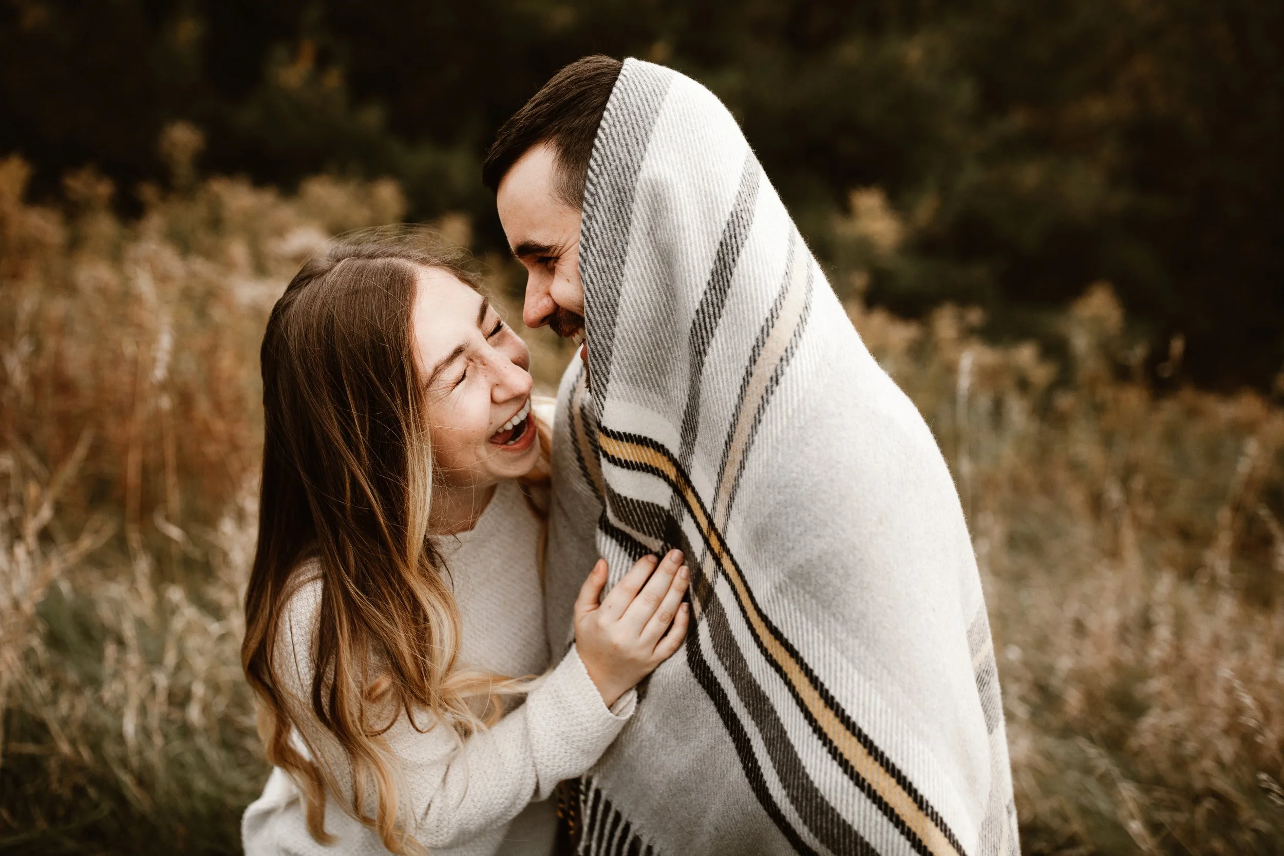 young couple wrapped in a blanket being silly