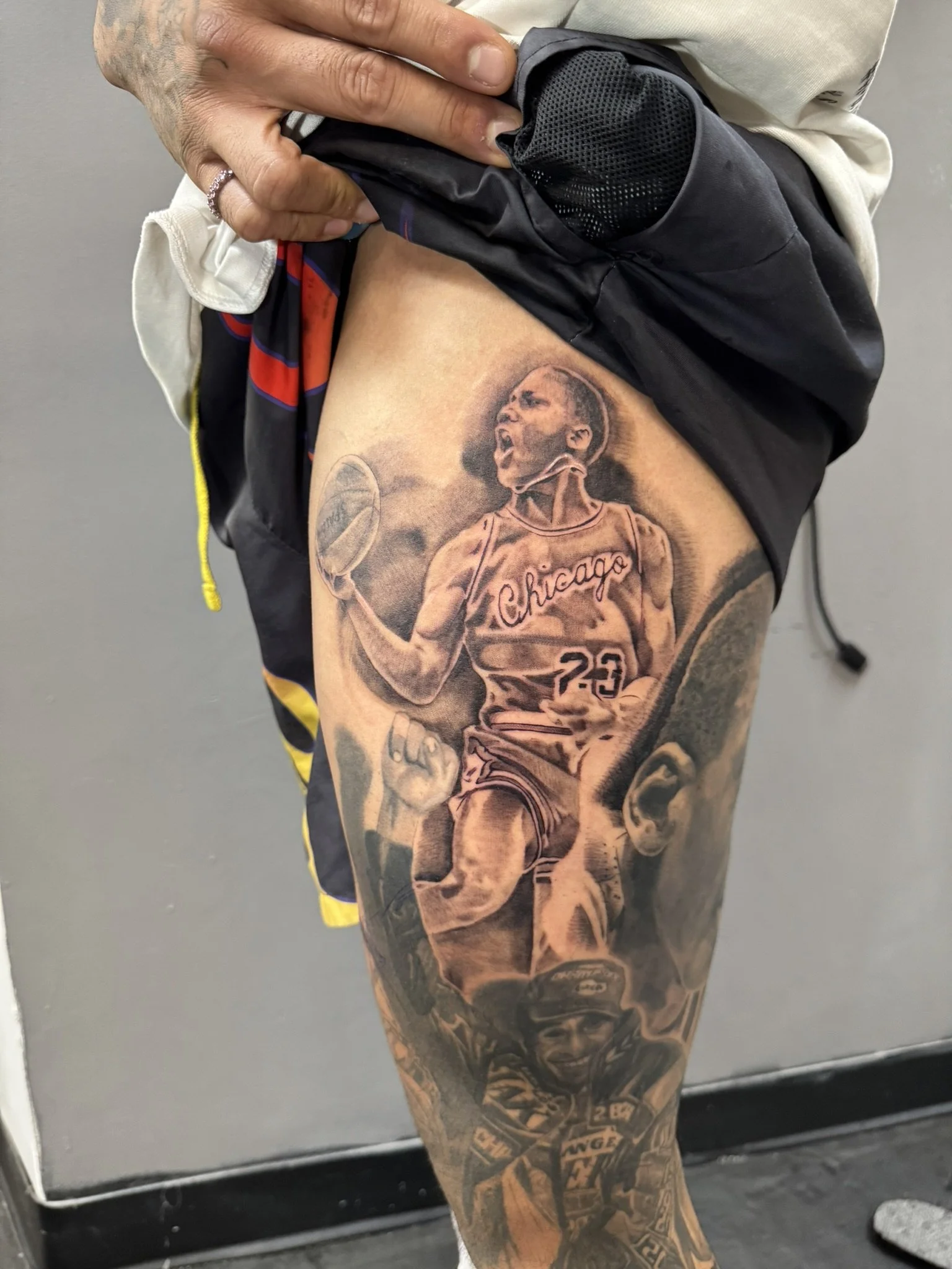 Close-up of a tattooed arm featuring a Chicago basketball player in jersey number 23 holding a basketball