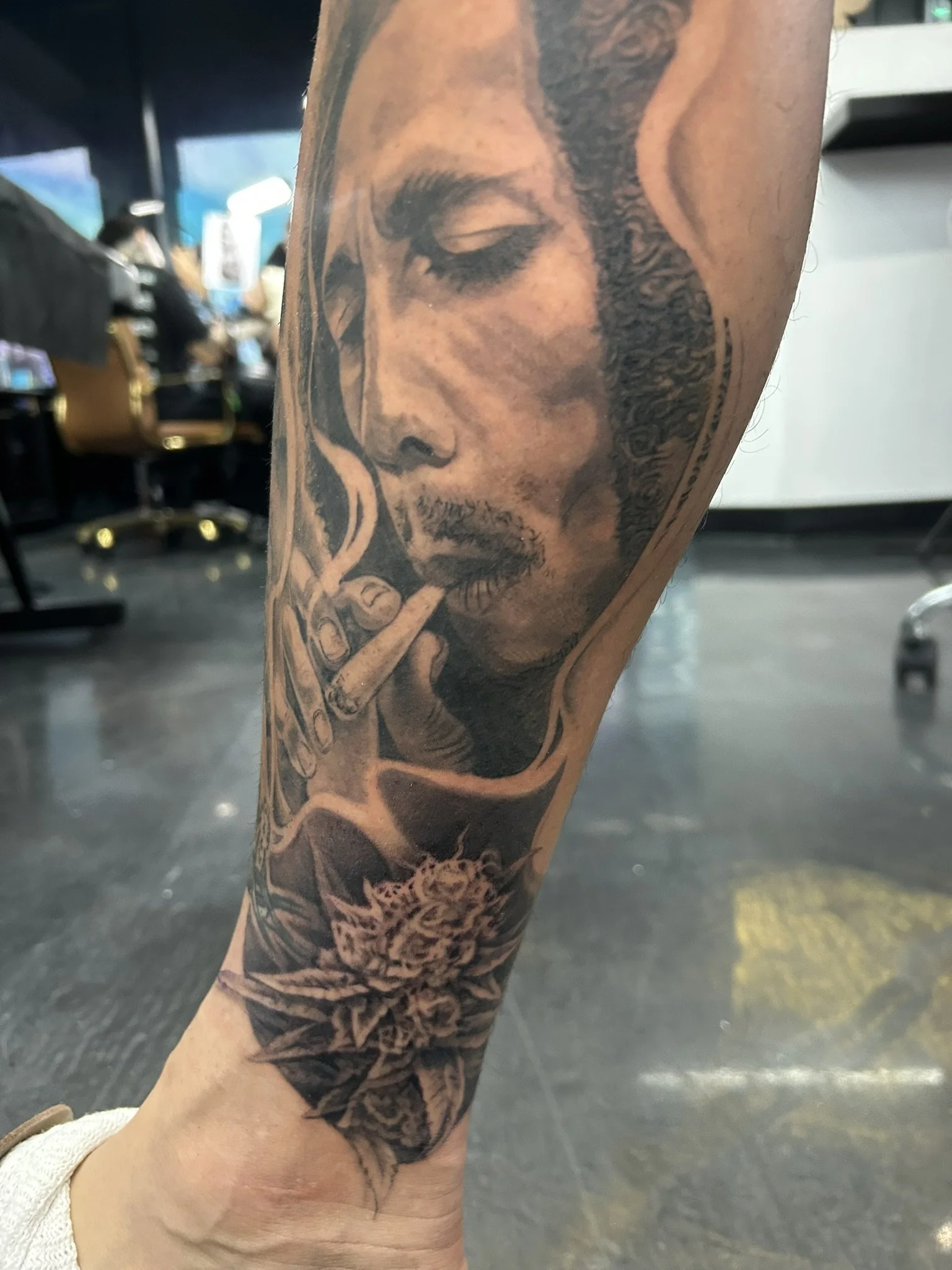 Close-up of an intricate black-and-gray tattoo depicting a bearded man smoking on a forearm.