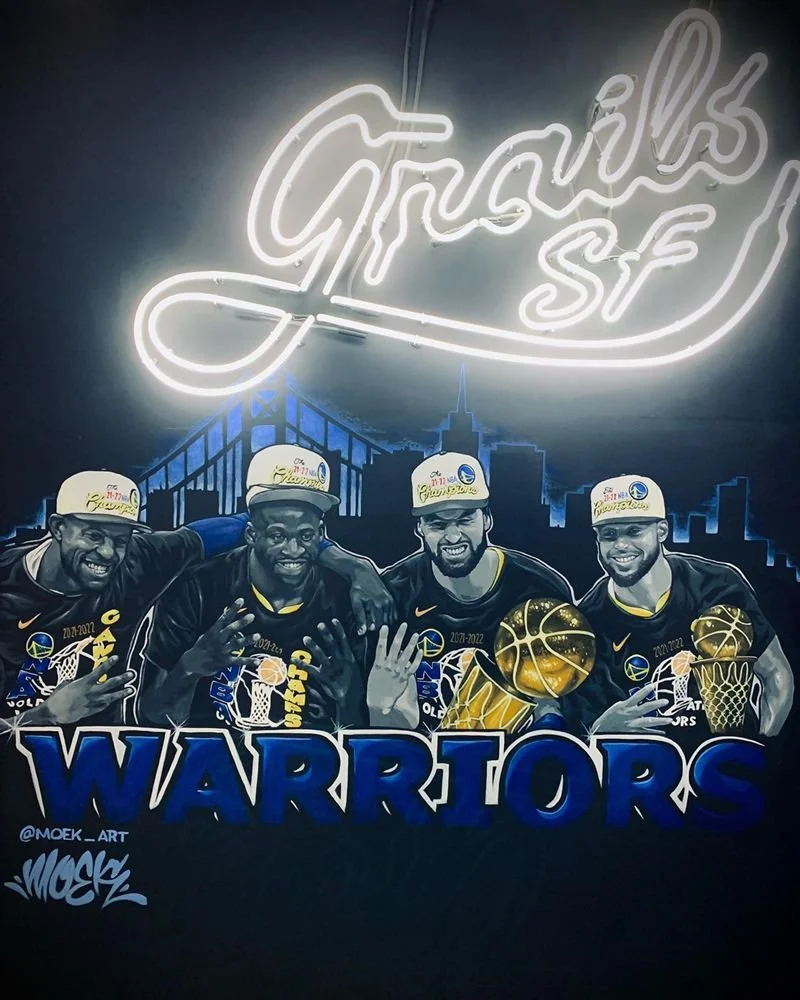 Illustrated mural of the Golden State Warriors' 2022 NBA championship team with players holding the championship trophy and basketballs beneath a glowing “Champions” sign.