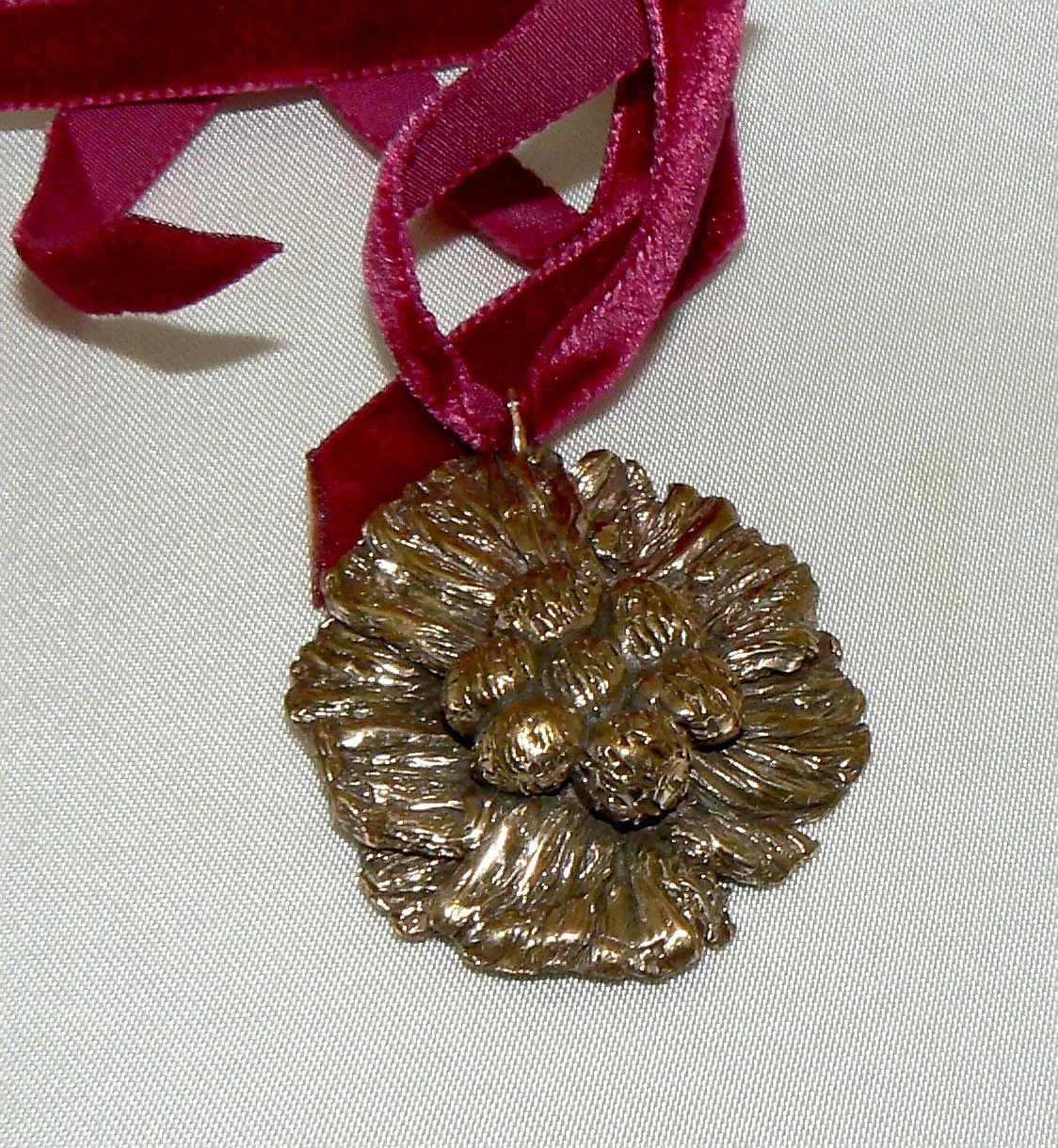 Bronze cast flower pendant on red ribbon, 45mm