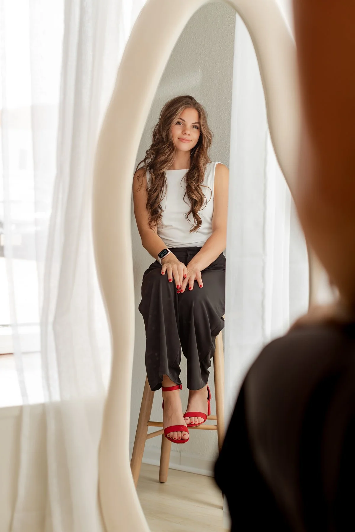 Portrait reflected in a mirror beside a bright window.