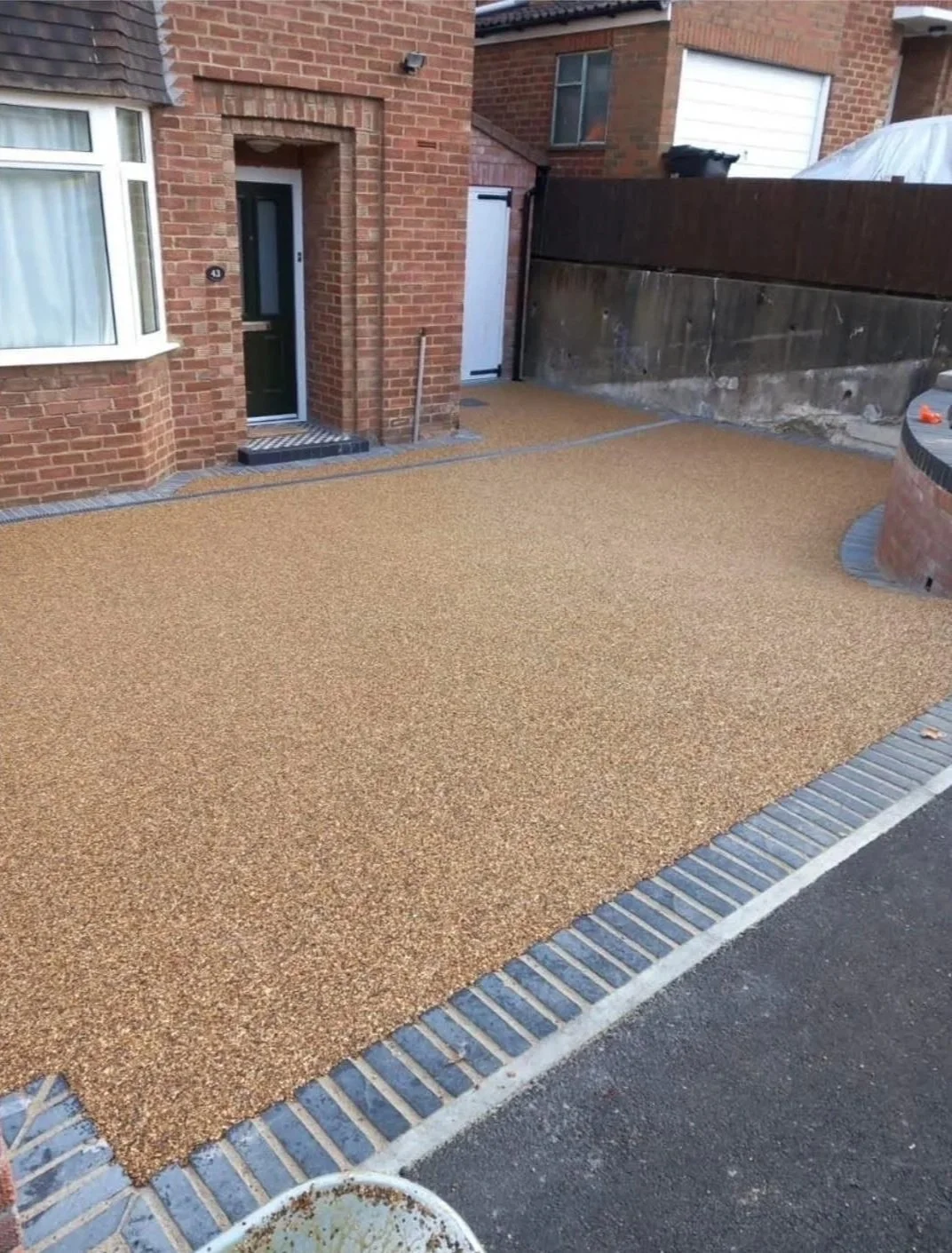 Resin-bound driveway with brick edging in front of a brick house