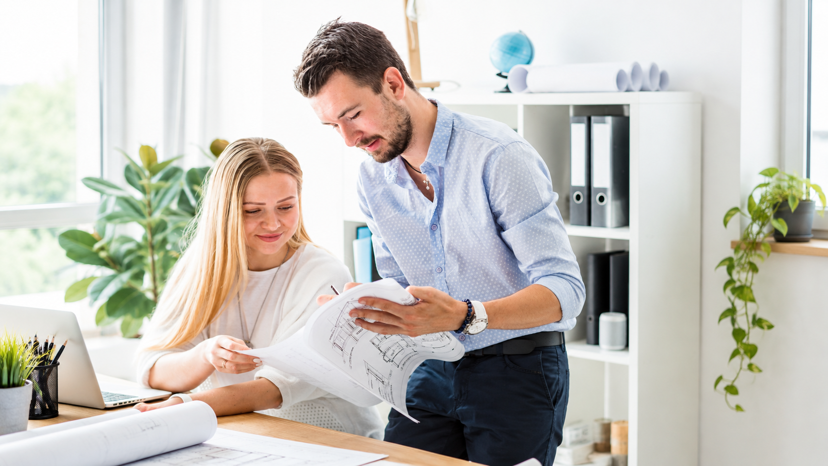 Architects reviewing blueprints together at a bright office desk