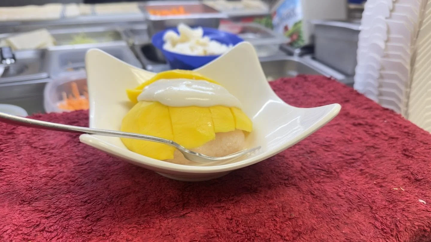 Mango slices with white cream on a dessert in a white bowl at a food counter