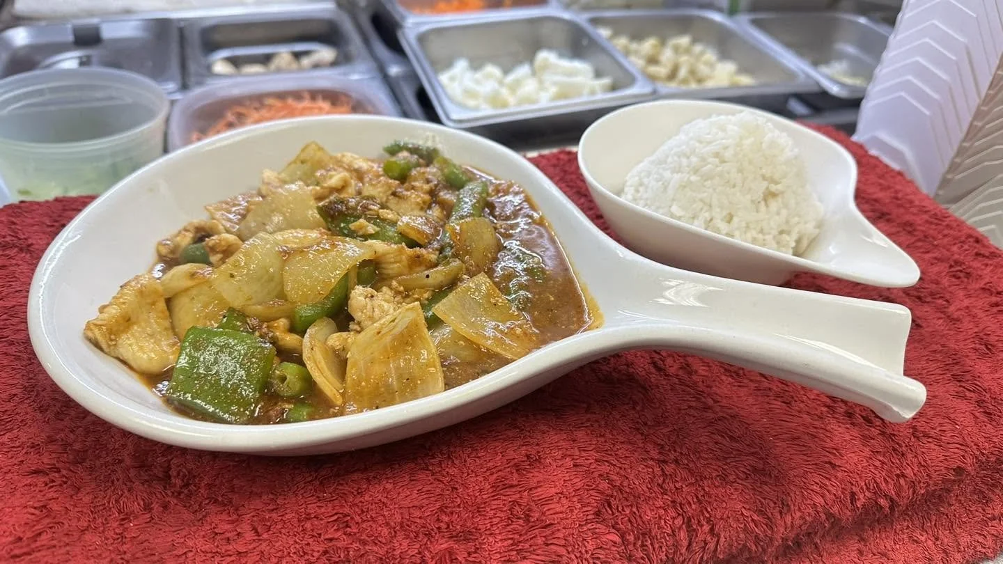 Chicken stir-fry with onions and green peppers in brown sauce, served with white rice at a buffet