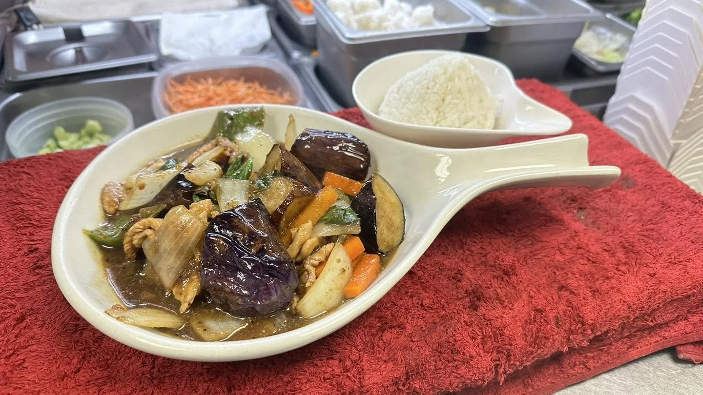 Stir-fried chicken with eggplant and mixed vegetables served with white rice in a restaurant kitchen