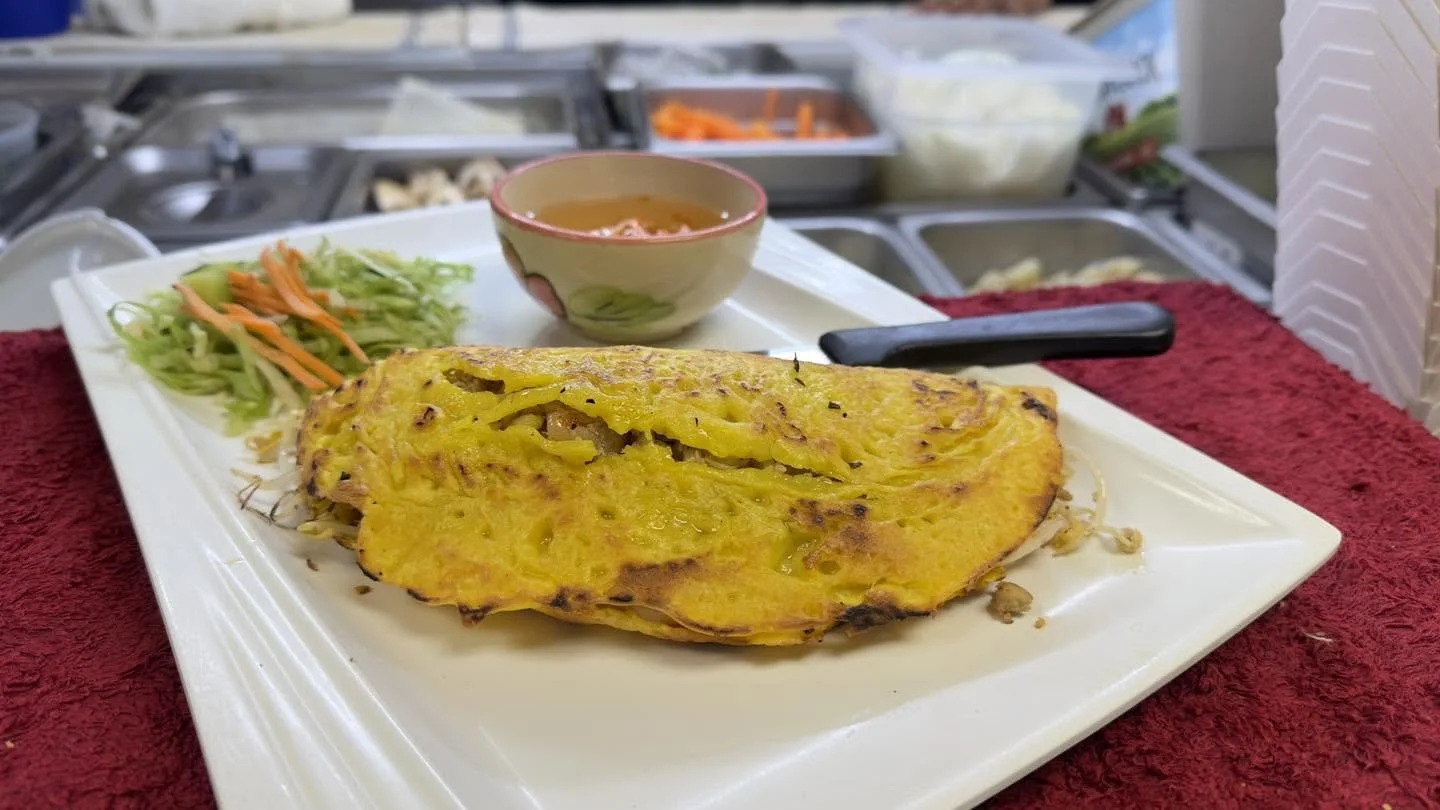 Golden stuffed flatbread served with shredded lettuce, carrots, and dipping sauce on a white plate