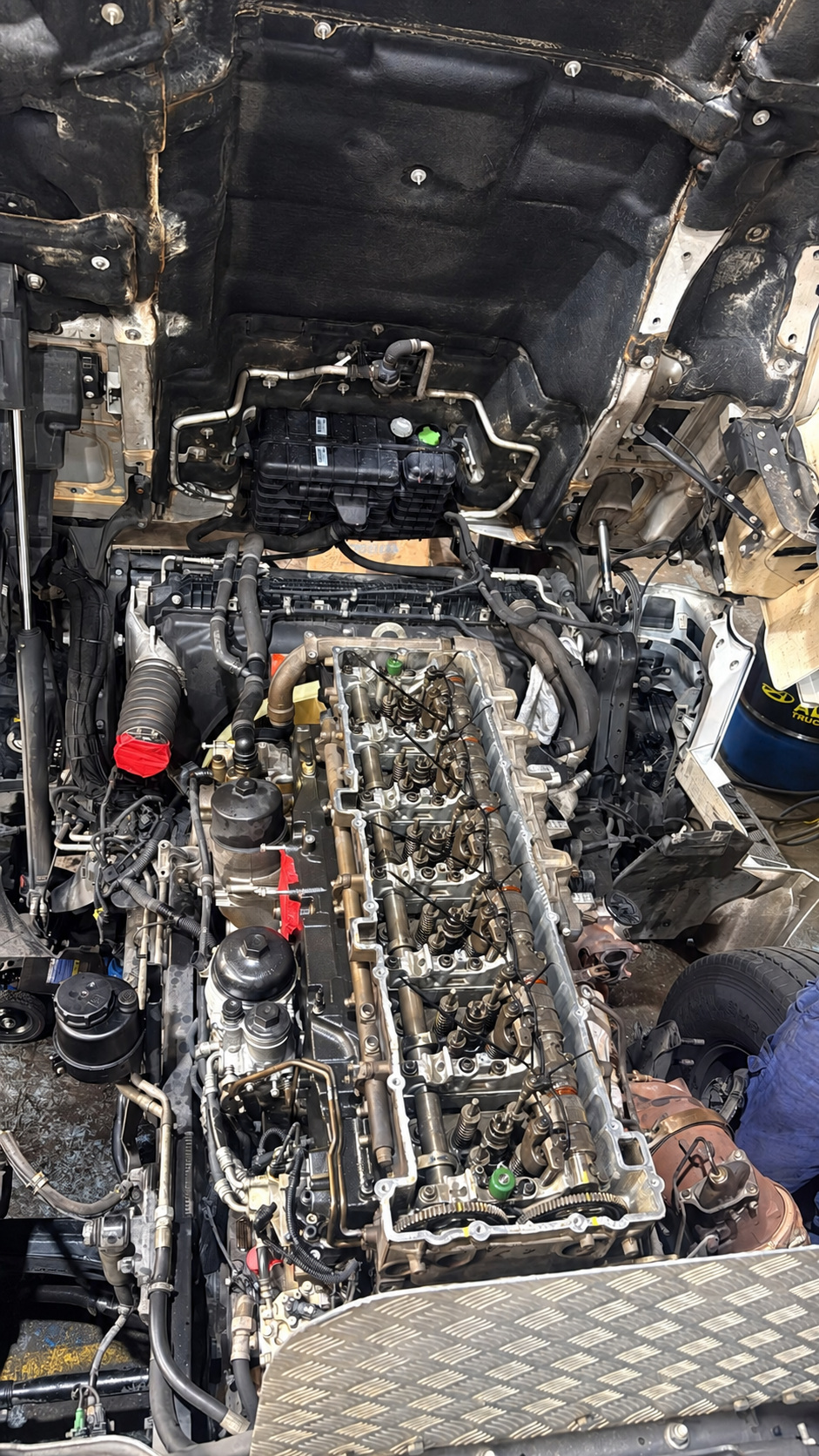 Exposed diesel truck engine with valve cover removed, showing cylinder head, camshafts, injectors, and rocker arms during repair