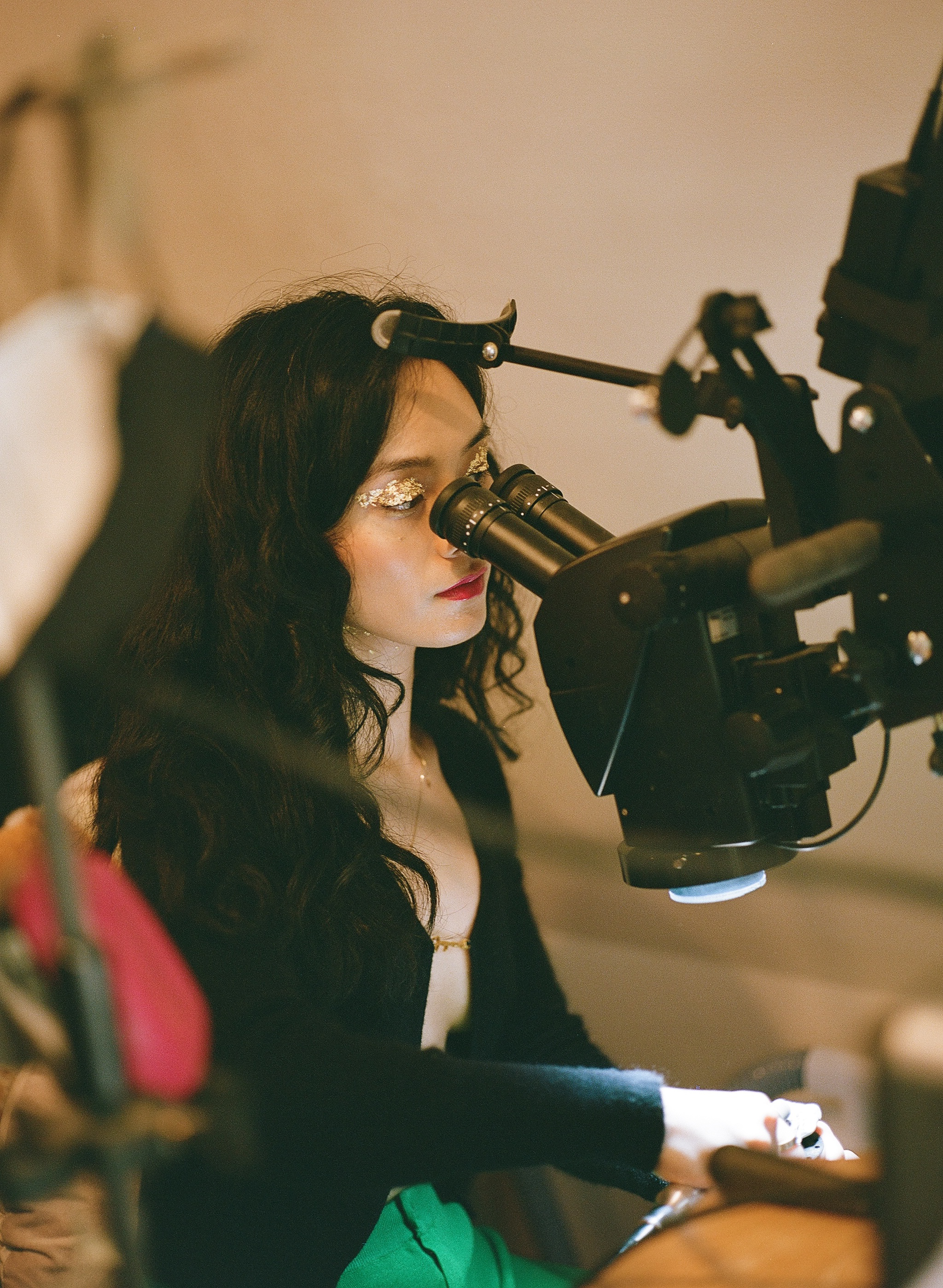 Woman with glitter eye makeup and horn-shaped headband operating a professional video camera