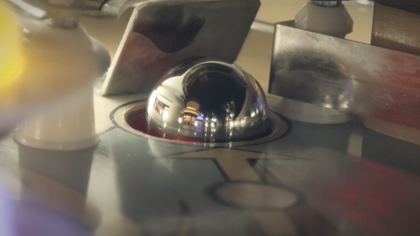 Close-up of a chrome dome-shaped control knob on a vintage jukebox panel