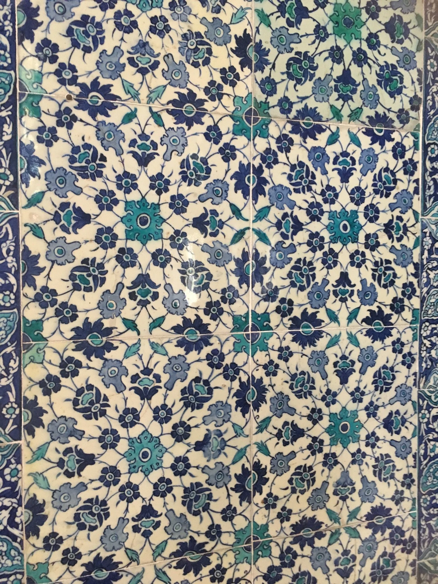 Close-up of blue, teal, and gray floral patterned ceramic tiles with decorative borders