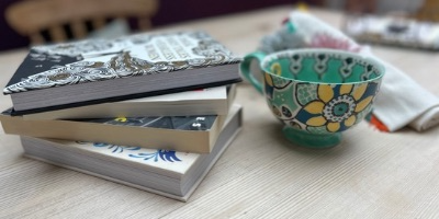 Stack of illustrated books beside a colorful patterned ceramic bowl on a table