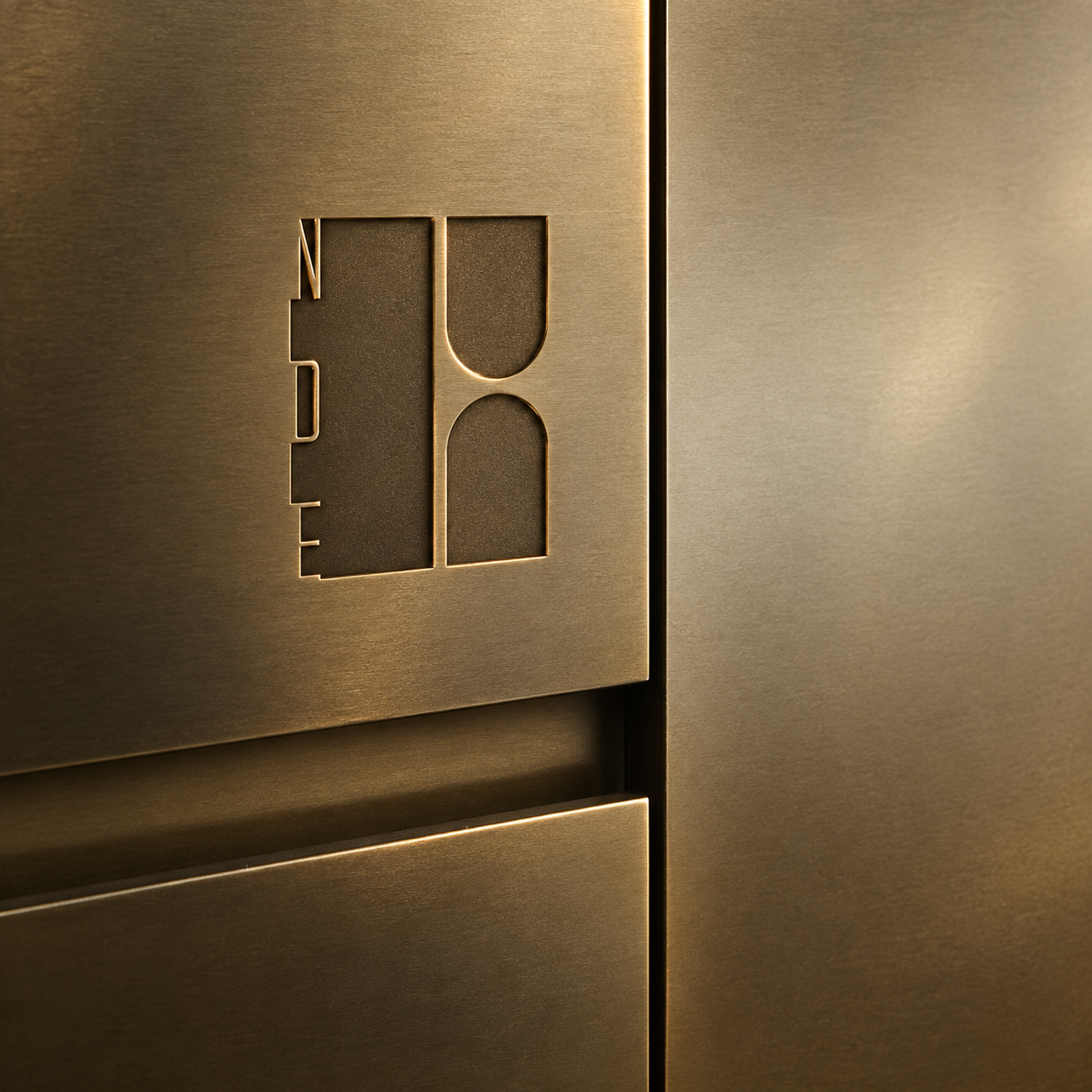 Close-up of a brushed bronze elevator door with a raised geometric symbol and warm accent lighting