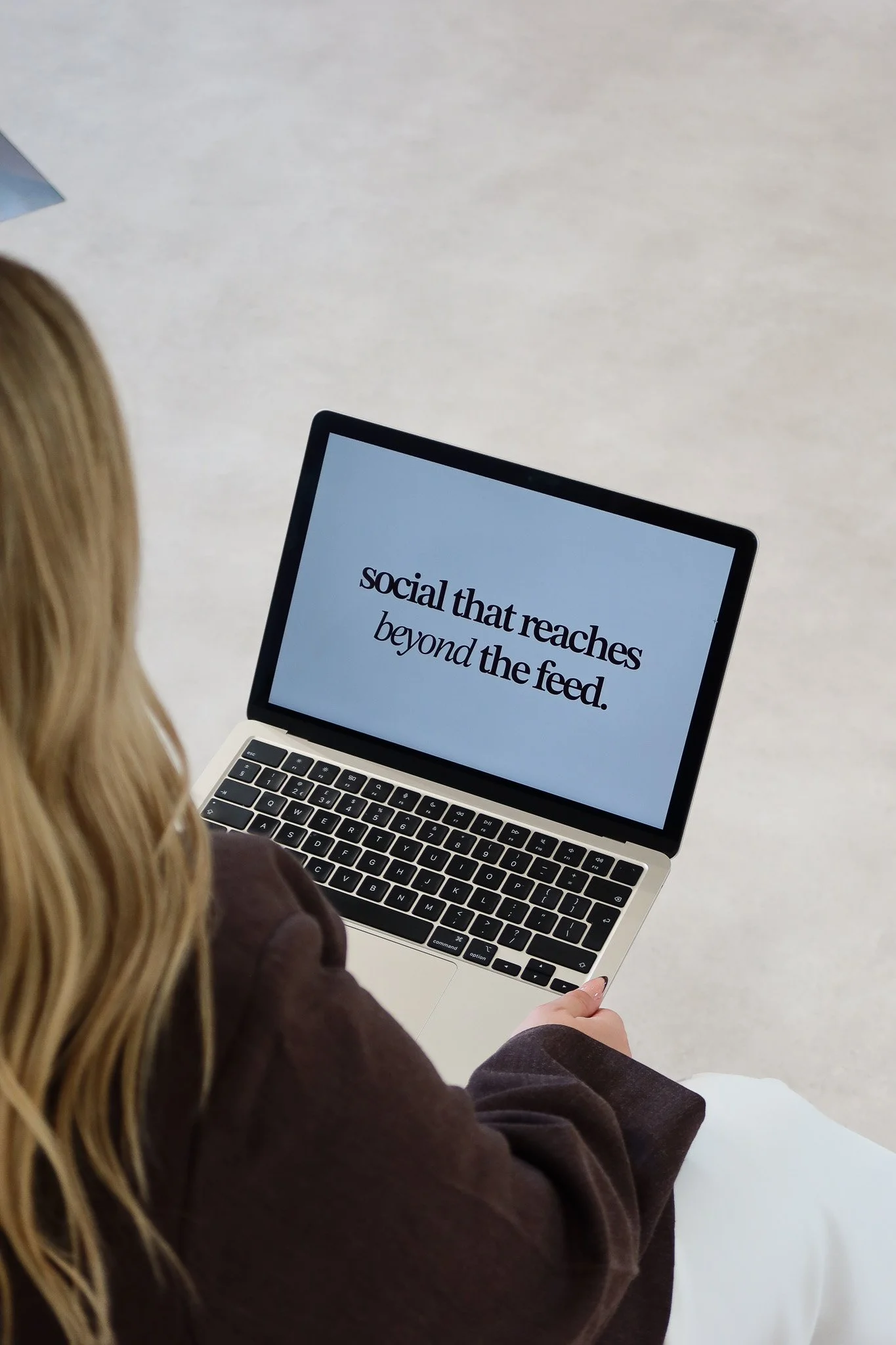 Laptop screen reading 'social that reaches beyond the feed.' on Lauren's lap