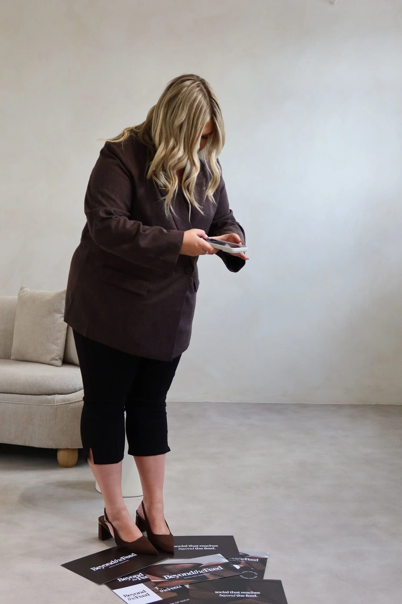 Creative director photographing printed brand collateral on an iPhone during a content shoot