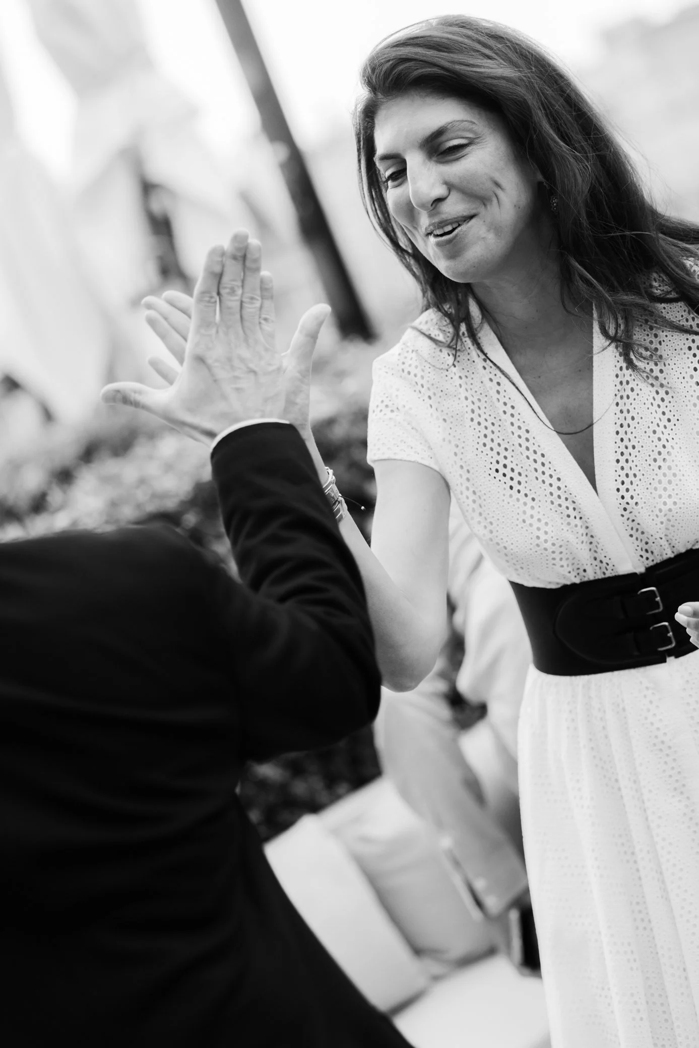Femme souriante discutant avec une personne en noir, main levée au premier plan, photo en noir et blanc