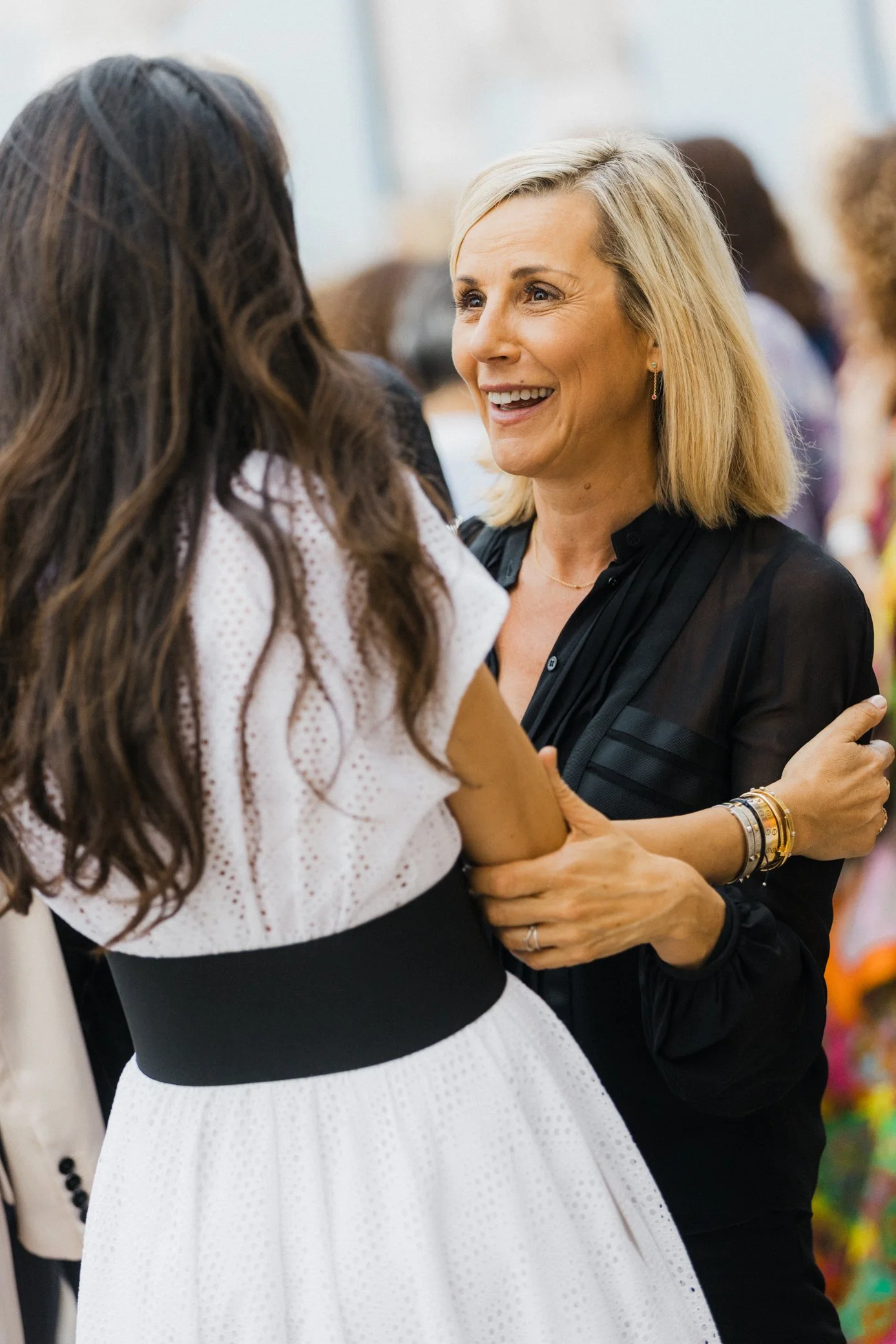 Deux femmes souriantes se saluent chaleureusement lors d’une rencontre conviviale.
