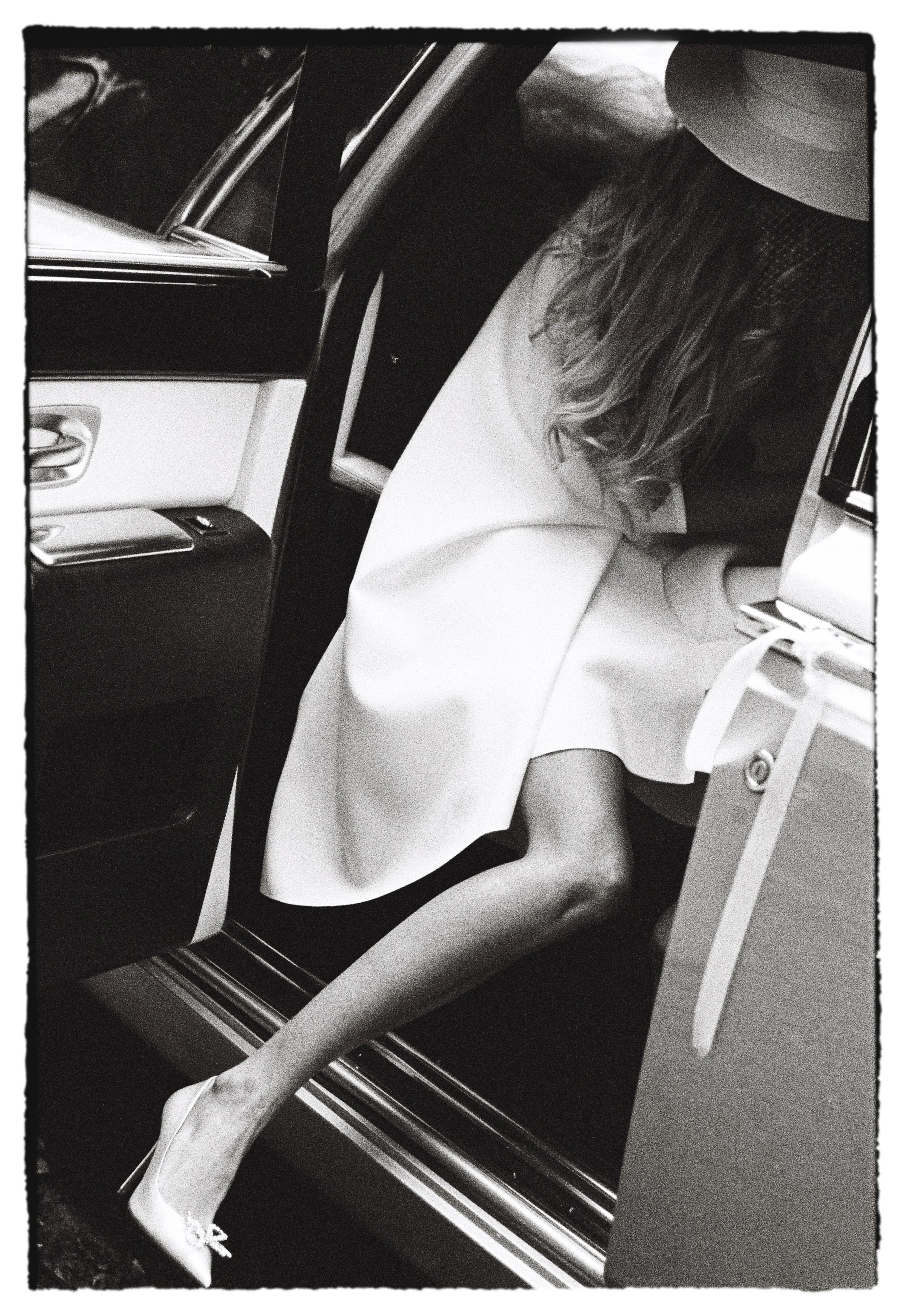 Portrait en noir et blanc d’une femme souriante assise dans un avion, près d’un hublot.