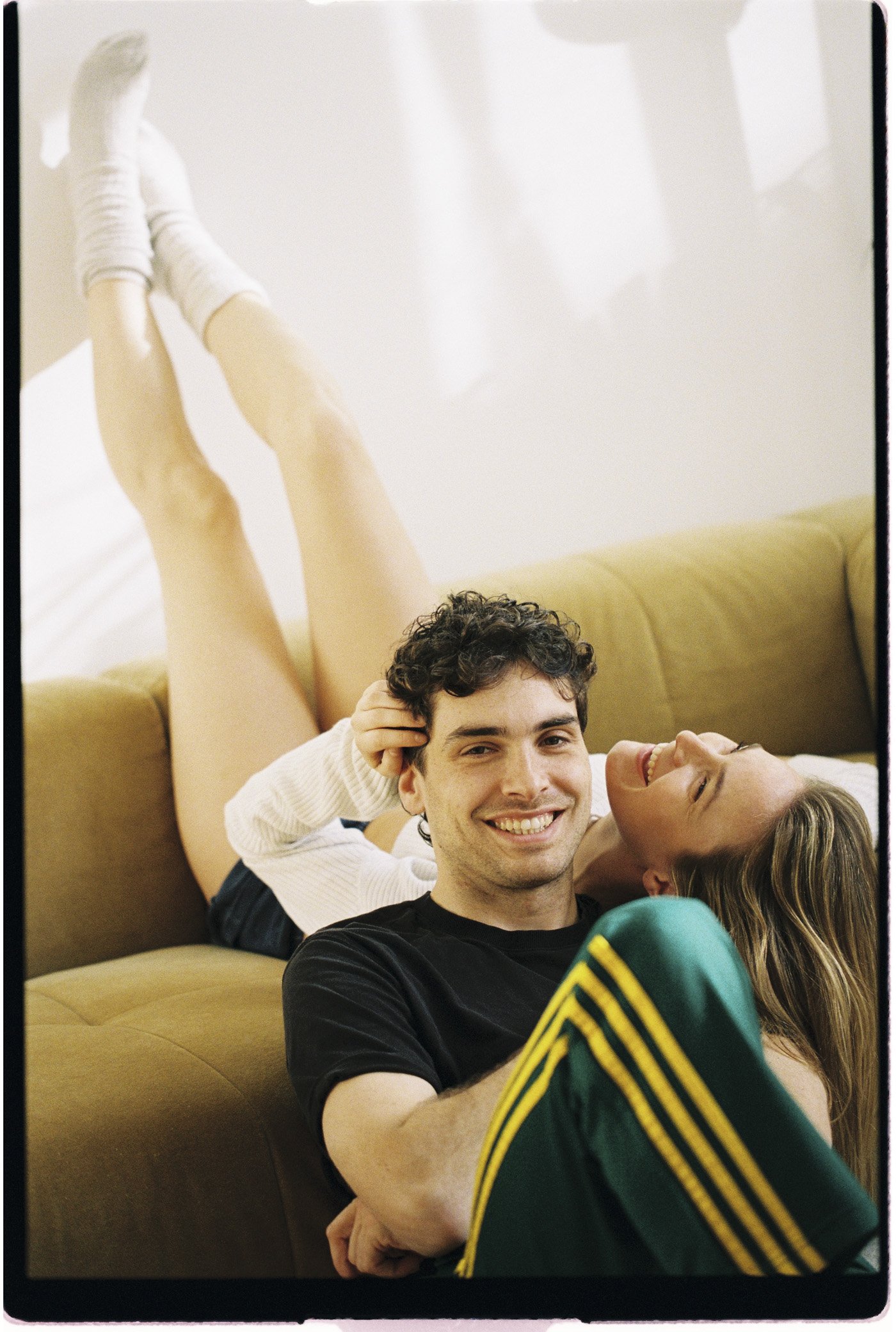 Jeune couple souriant et détendu sur un canapé, les jambes levées.