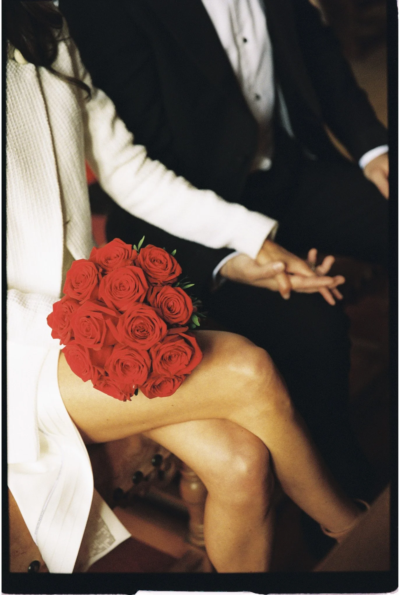 Couple de mariés échangeant leurs bagues, la mariée tenant un bouquet de roses rouges.