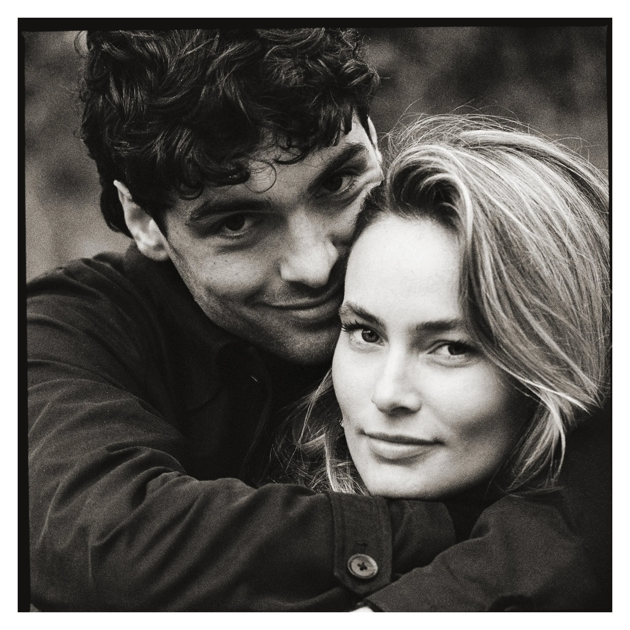 Portrait en noir et blanc d’un couple enlacé, souriant face à l’objectif.