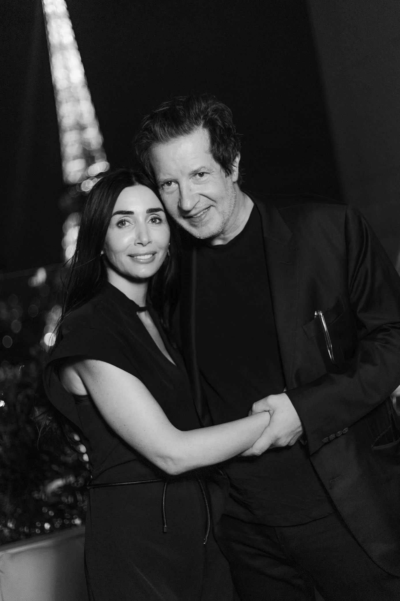 Portrait en noir et blanc d’un homme et d’une femme souriants, enlacés lors d’un événement.