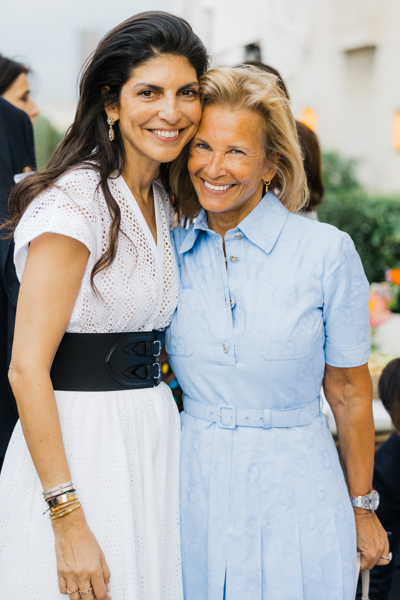 Deux femmes souriantes posant ensemble lors d’un événement en plein air.