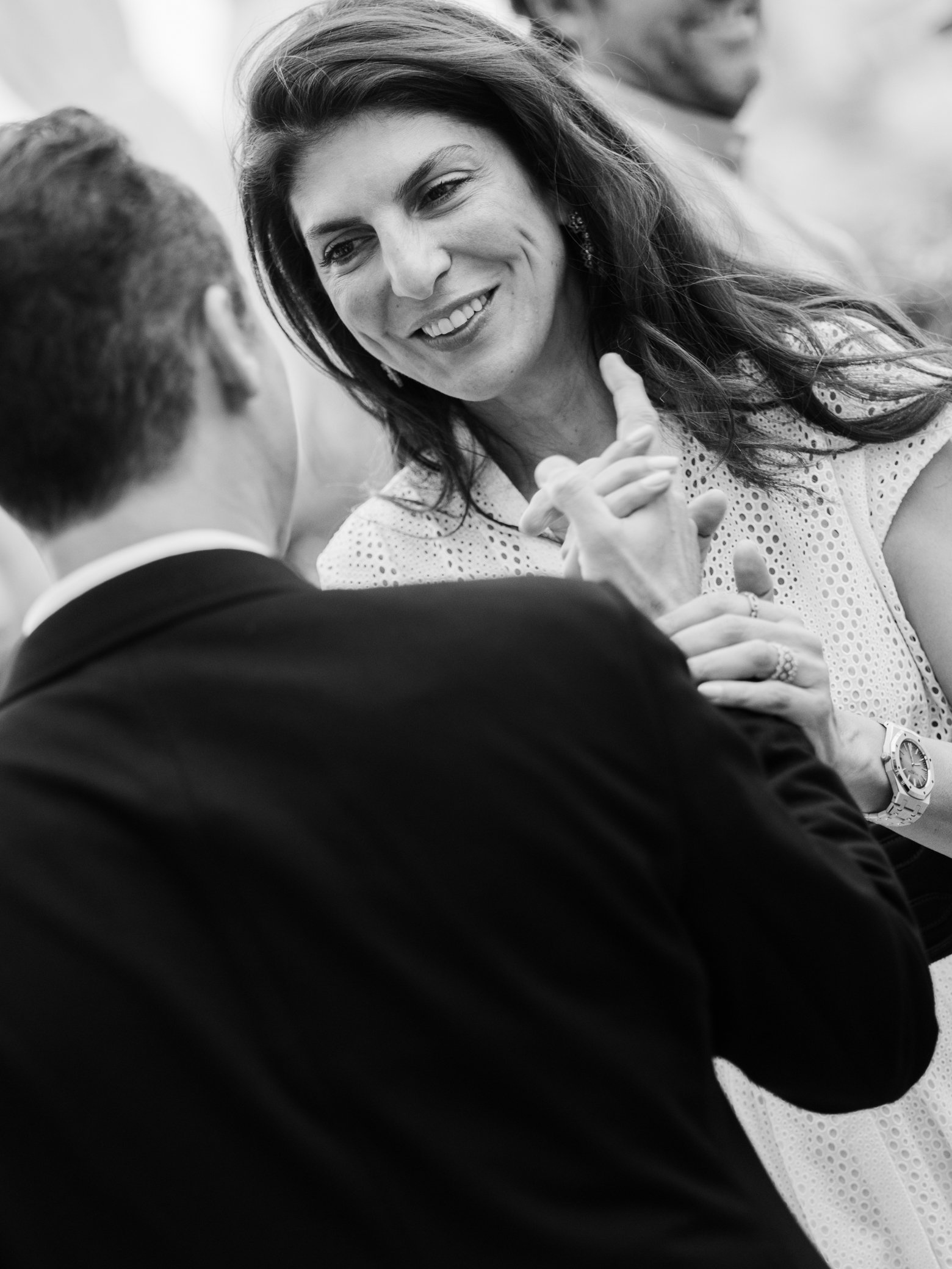 Portrait en noir et blanc d’une femme souriante faisant face à un homme en costume lors d’un échange convivial.