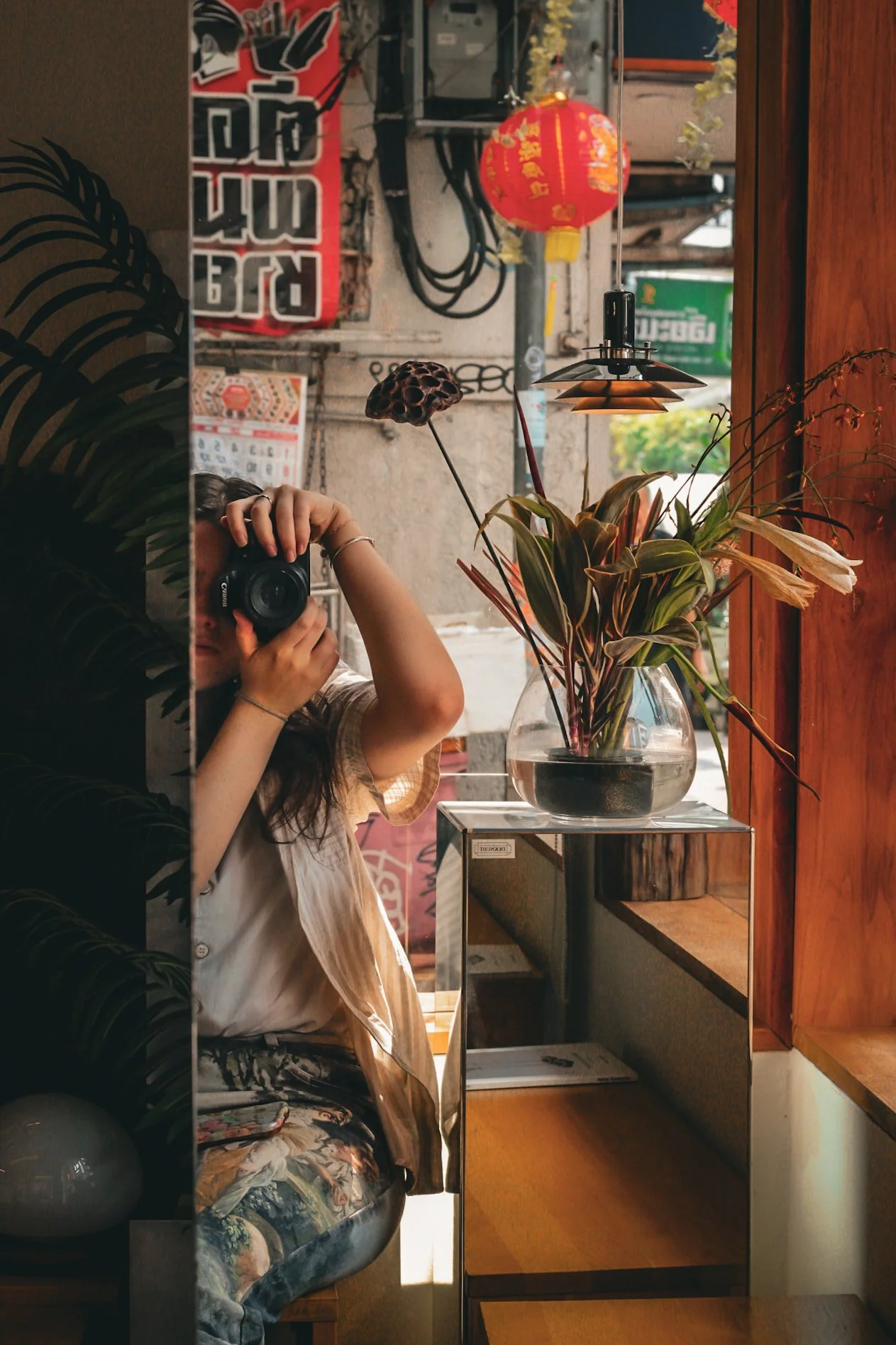 Photographer Jasmine Williams takes self portrait in a Bangkok cafe mirror.