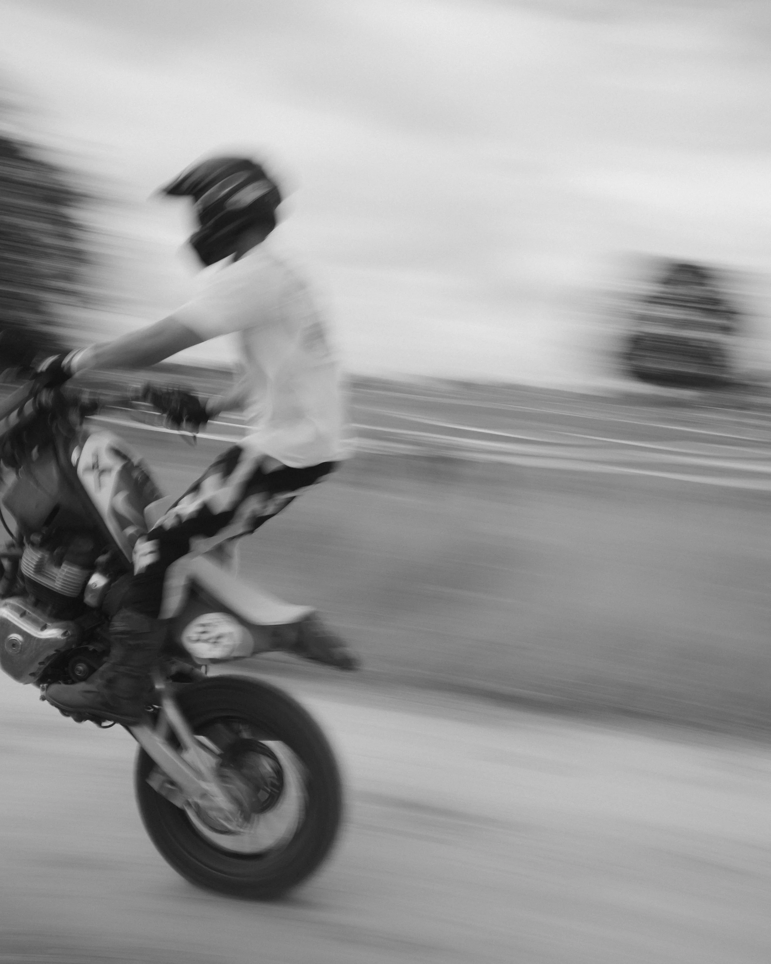 Black-and-white motion-blurred motorcycle rider speeding on a racetrack