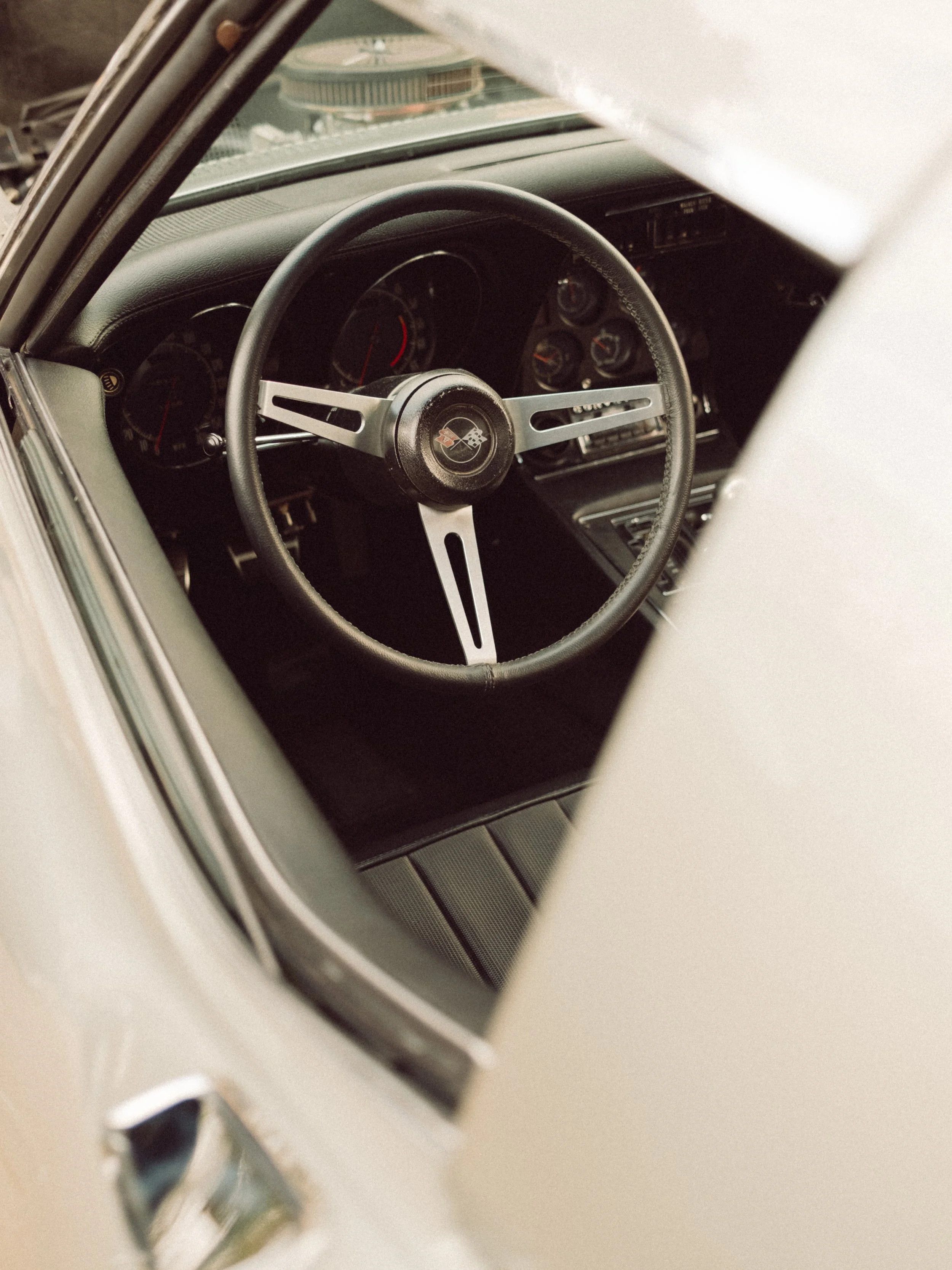 Interior view of a vintage Chevrolet Corvette showing the steering wheel, dashboard, gauges, and center console
