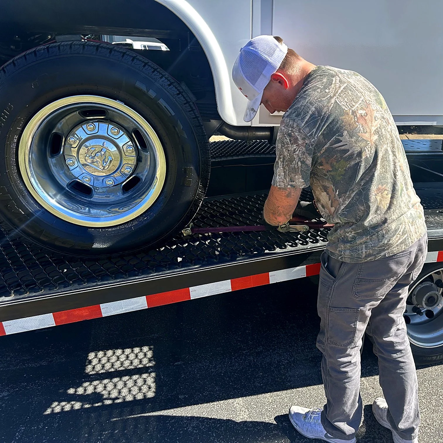 Tri State Cargo driver securing a vehicle wheel strap on an open car hauler
