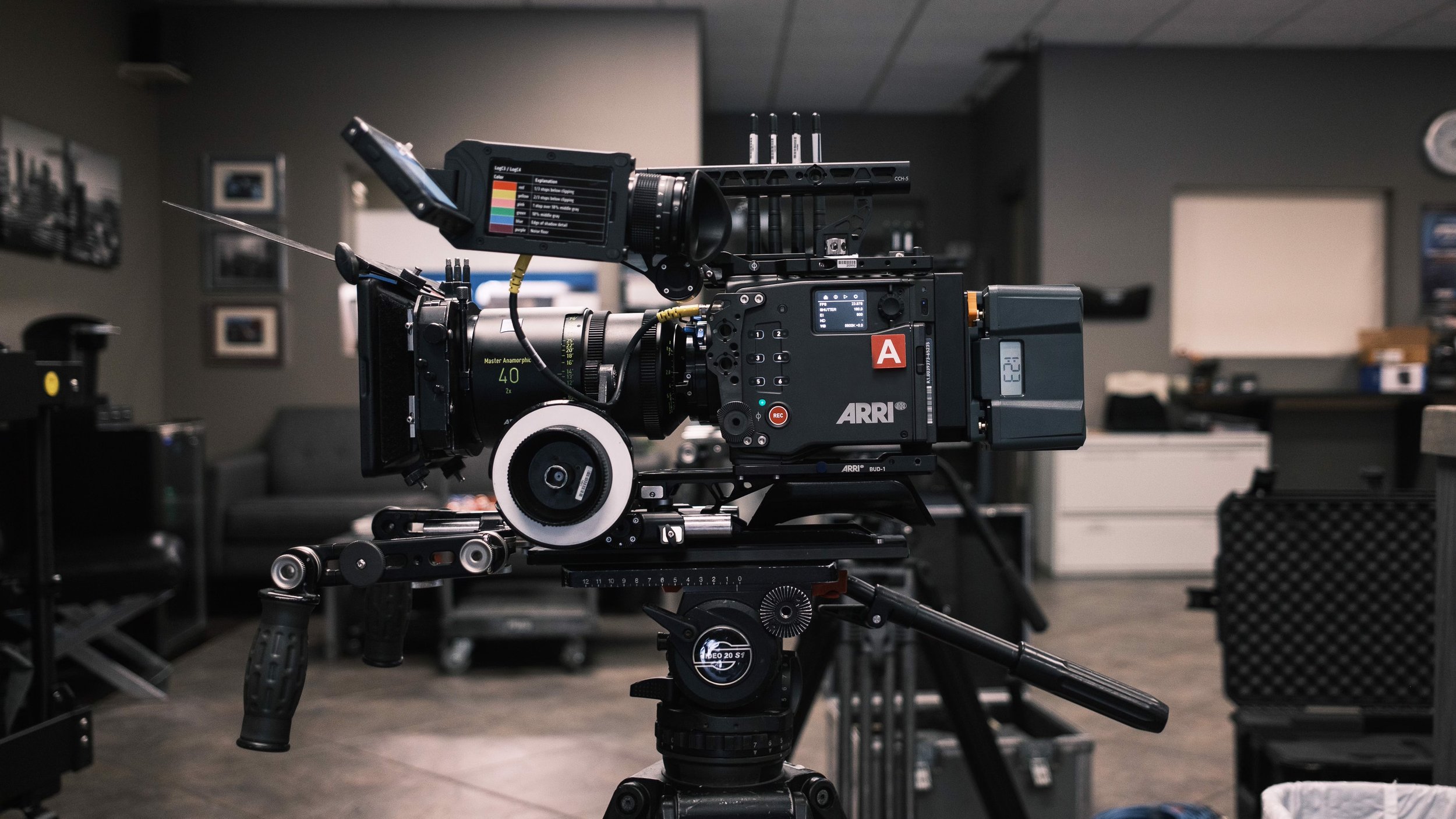 Professional ARRI cinema camera with anamorphic lens, monitor, and rig mounted on a tripod in a film studio